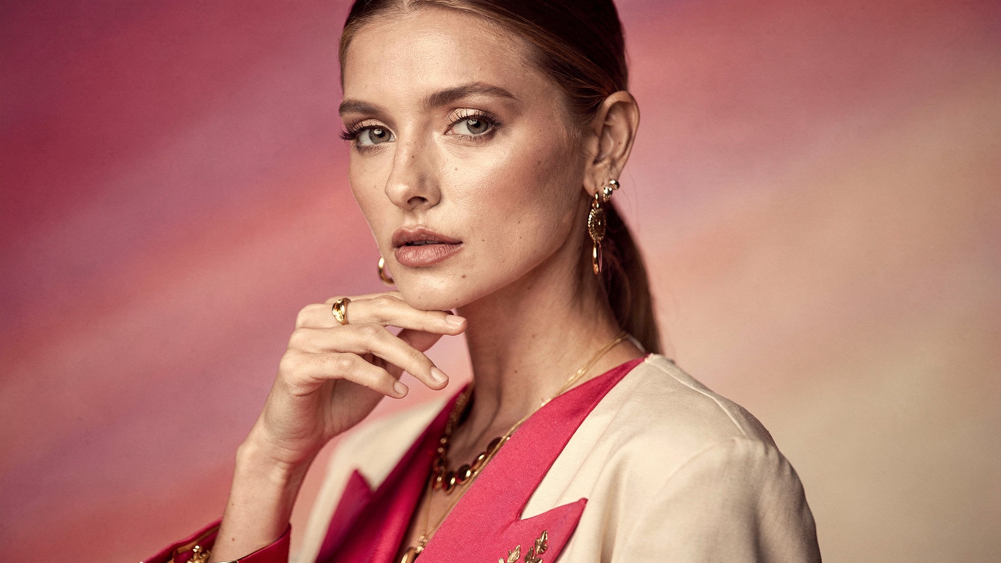 Creator with a thoughtful cautious expression, hand near her chin, in a moody pink studio