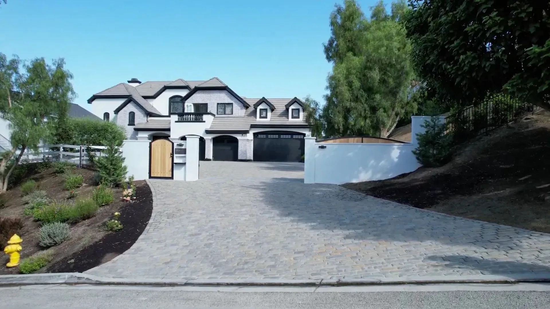 Broad gray paver driveway leading to a white two-story home