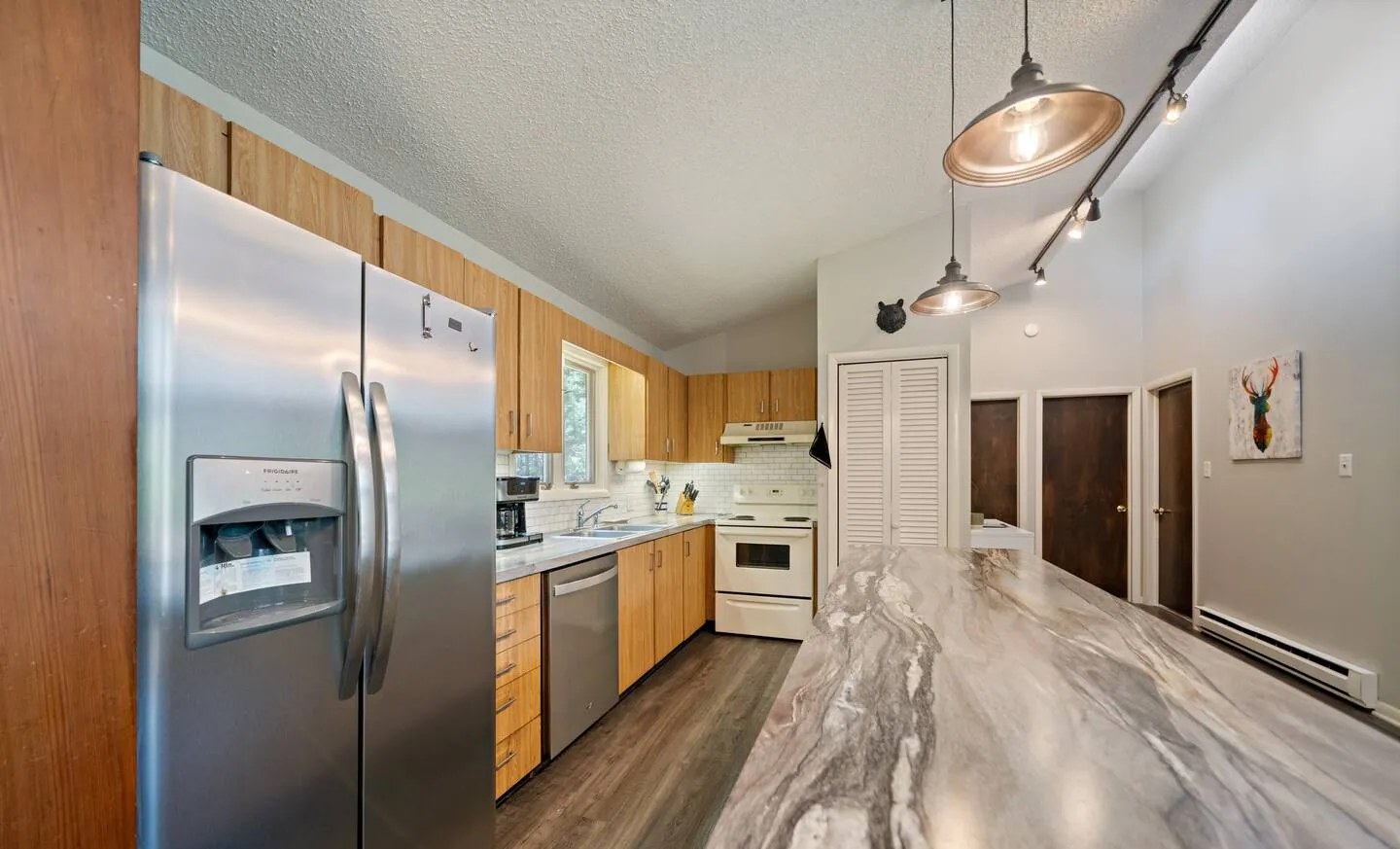 Kitchen with stainless fridge, wood cabinets and pendant lights at Lake Front, Lake Naomi