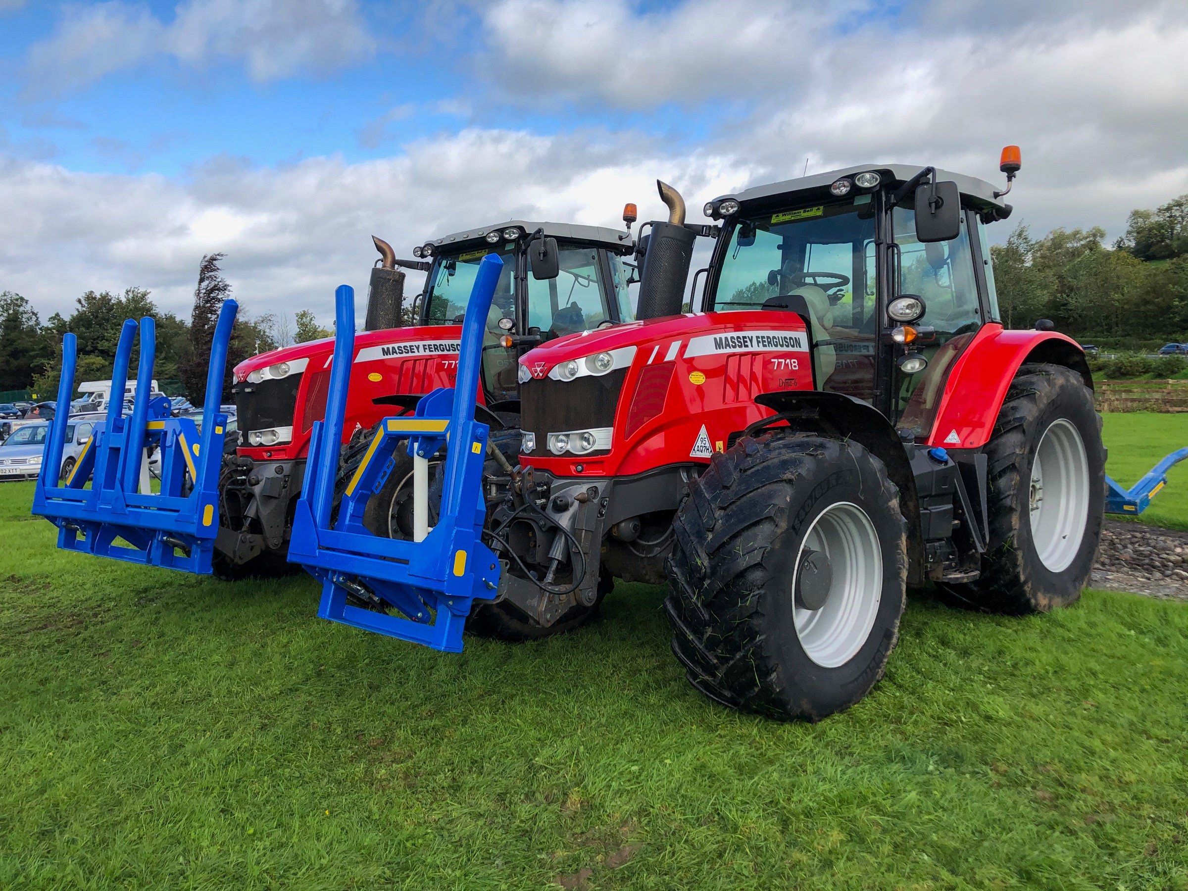 Massey Ferguson Two red tractors in a field side by side with blue Hydraulic folding bale handlers attached