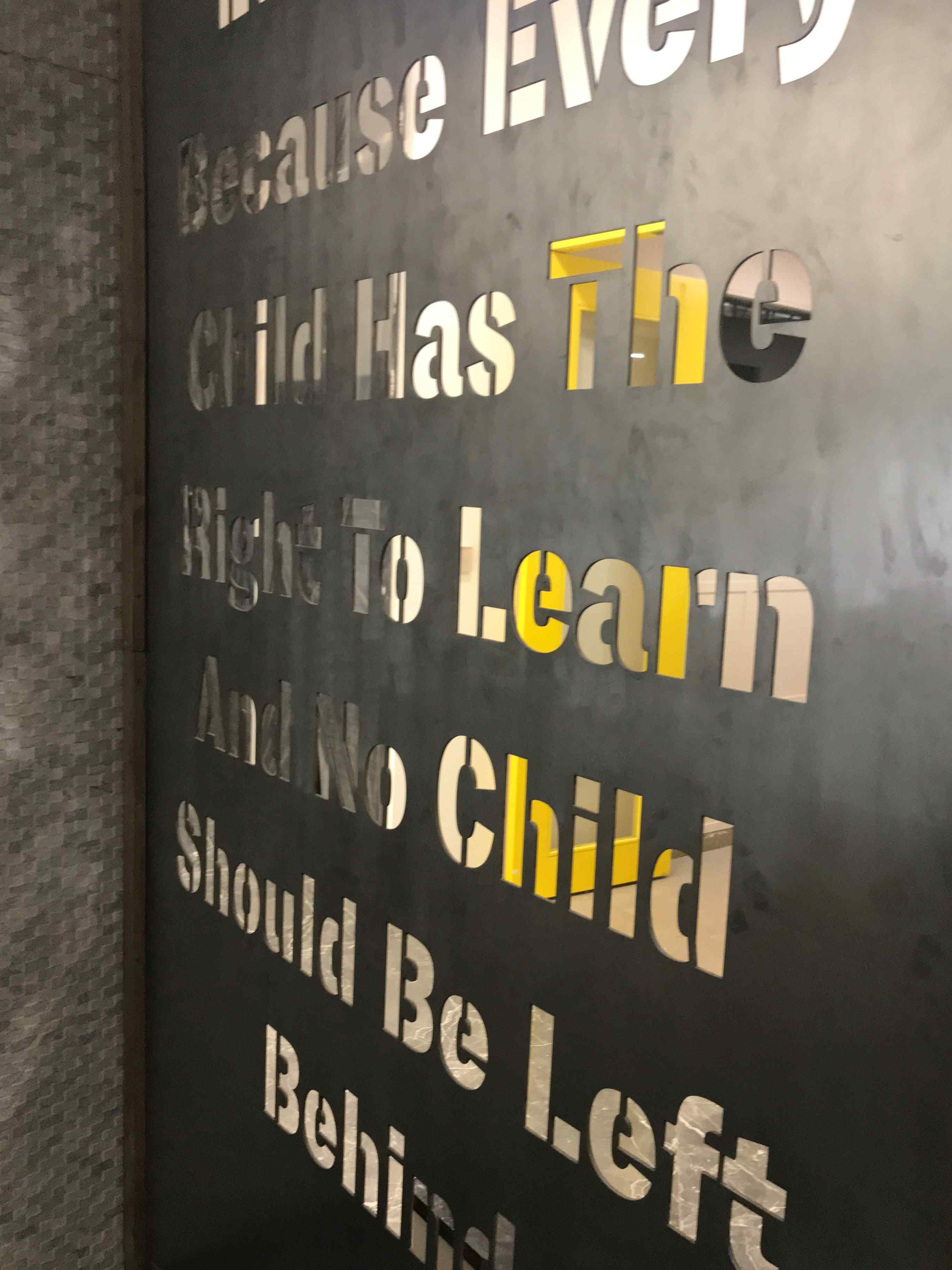 Nature-inspired preschool entrance with sculptural tree partitions and suspended green leaf ceiling panels.