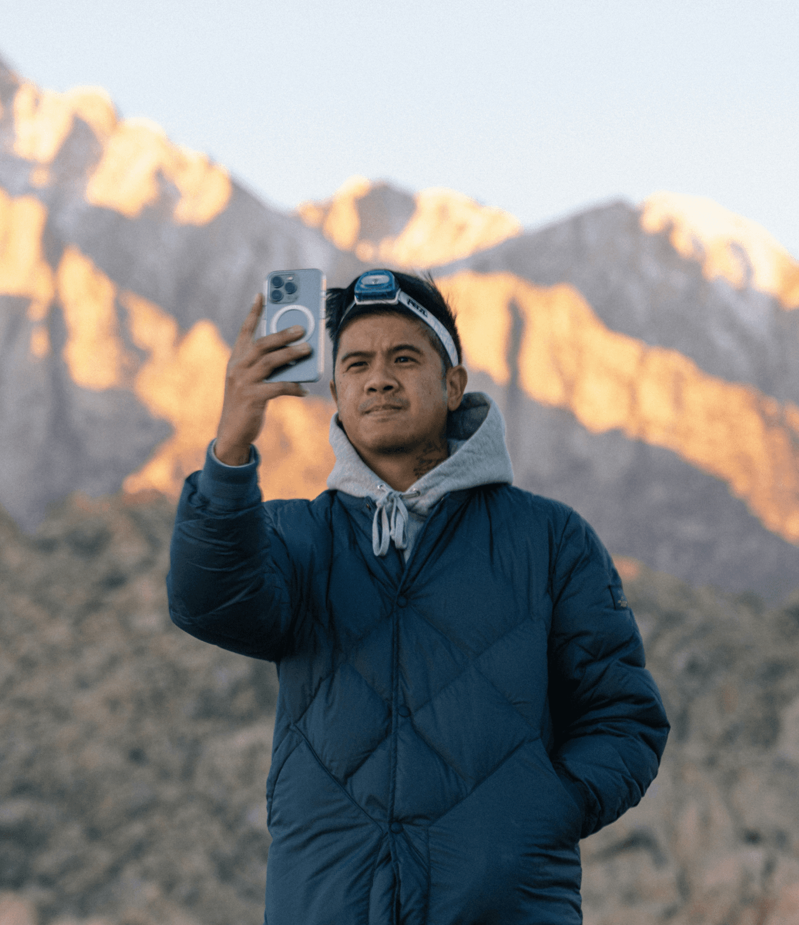 Man holding iPhone in front of mountain.