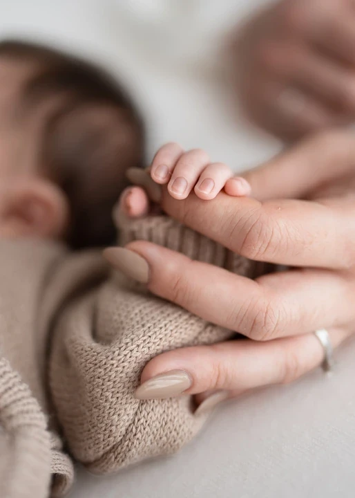 Newborn hand resting against an adult finger