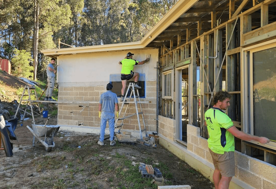 A photo of a house under construction, with hempcrete blocks being installed in the walls.