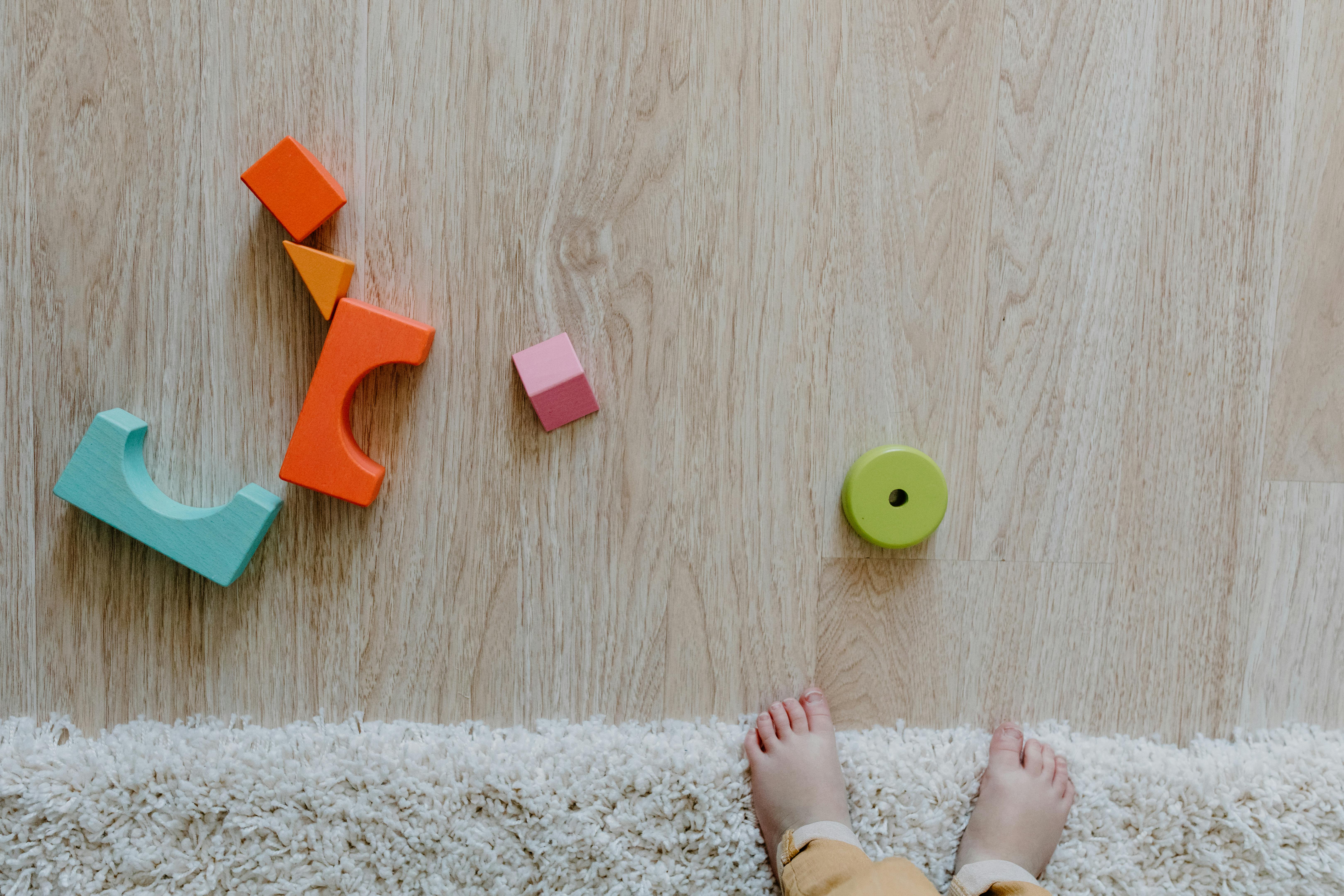 Kids’ toys scattered across a light wood floor with bare feet nearby — scratch-resistant, low-maintenance flooring that works for busy Brisbane households