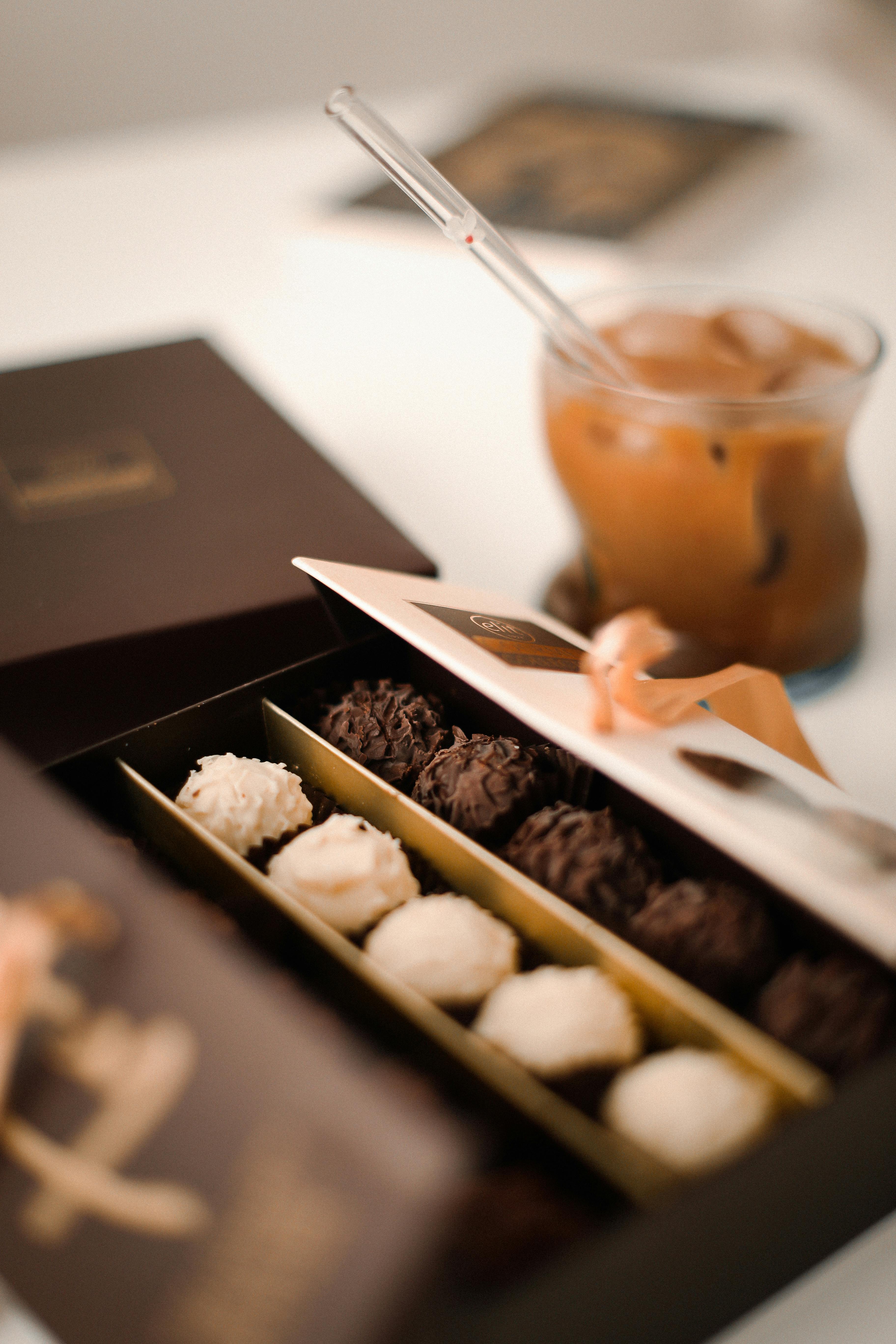 gourmet-chocolate-pralines-in-an-open-box-beside-an-iced-coffee,-creating-a-cozy - amine (pexels)