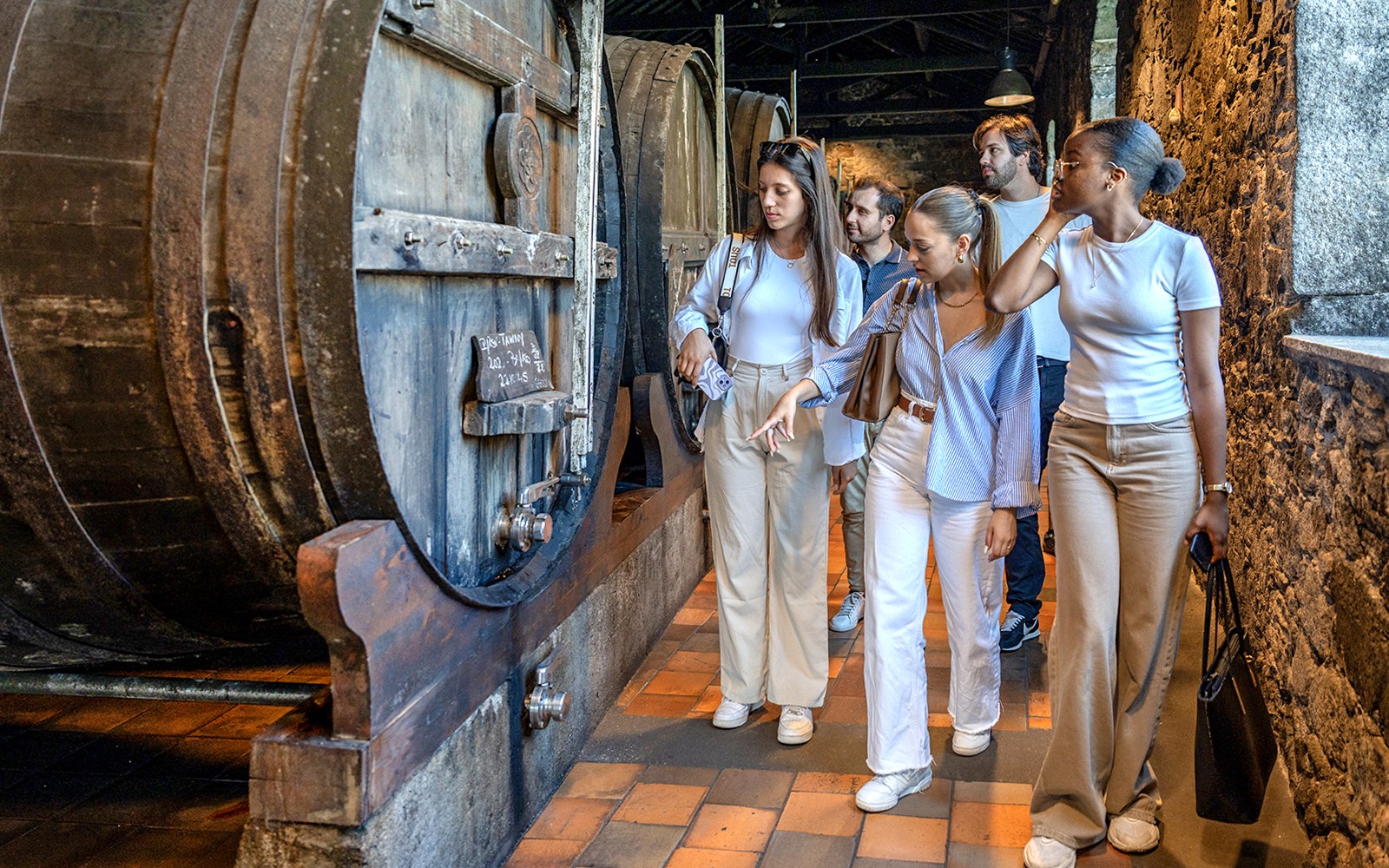 在波尔图团体游览大型葡萄酒桶的酒窖。