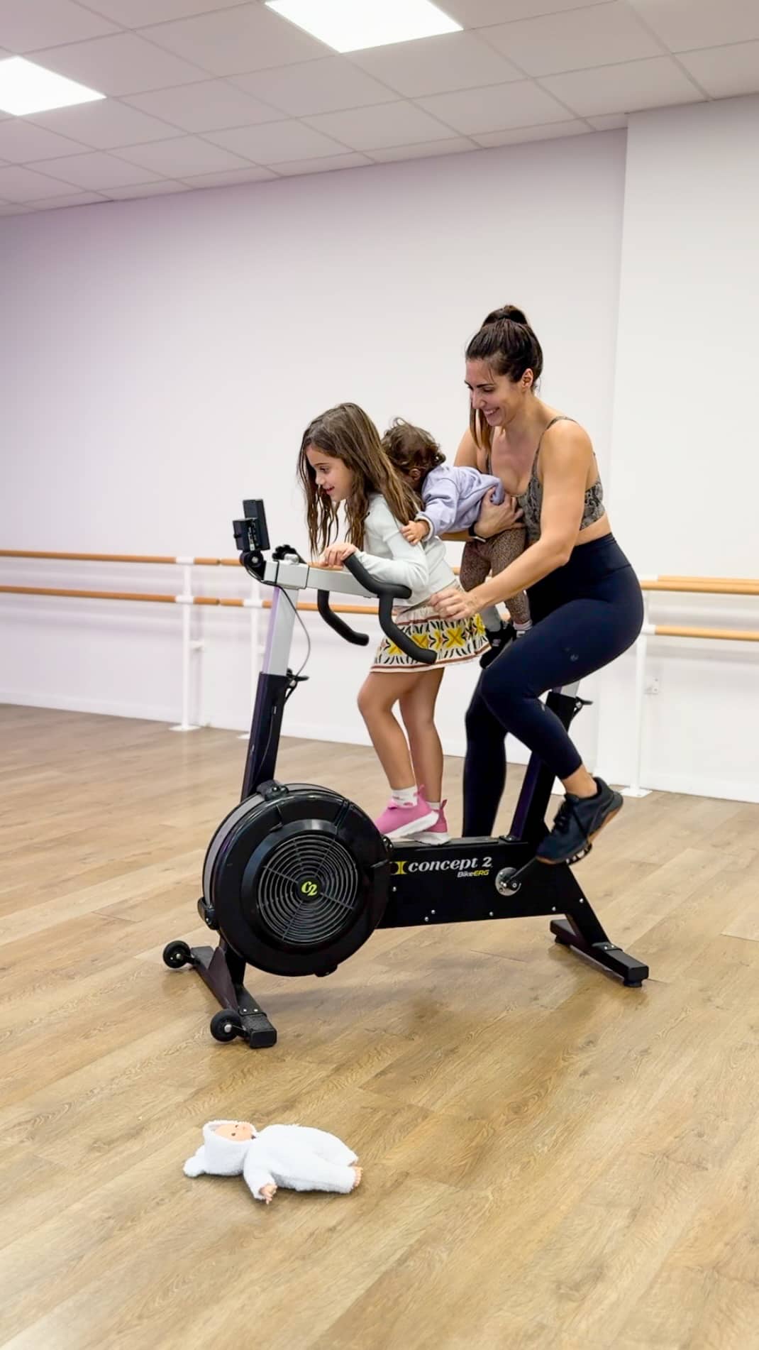 Une maman fait du vélo d’appartement avec ses deux enfants lors d’une séance de sport en famille.