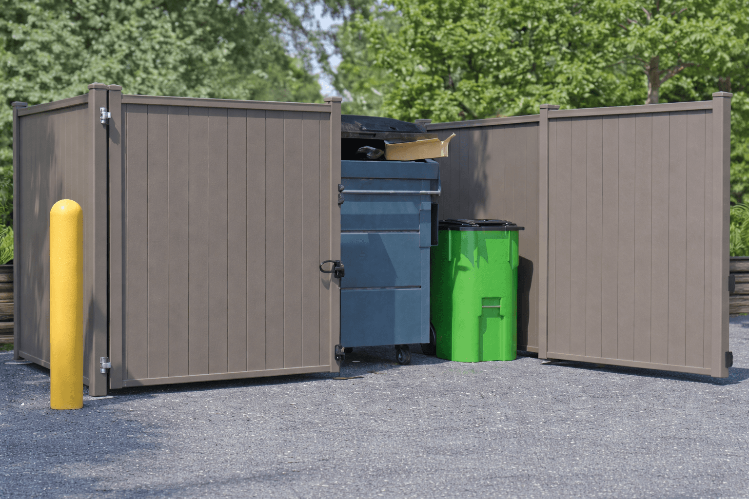 A commercial garbage enclosure made of grey louvered aluminum privacy panels, with open double gates revealing a blue and a green dumpster.