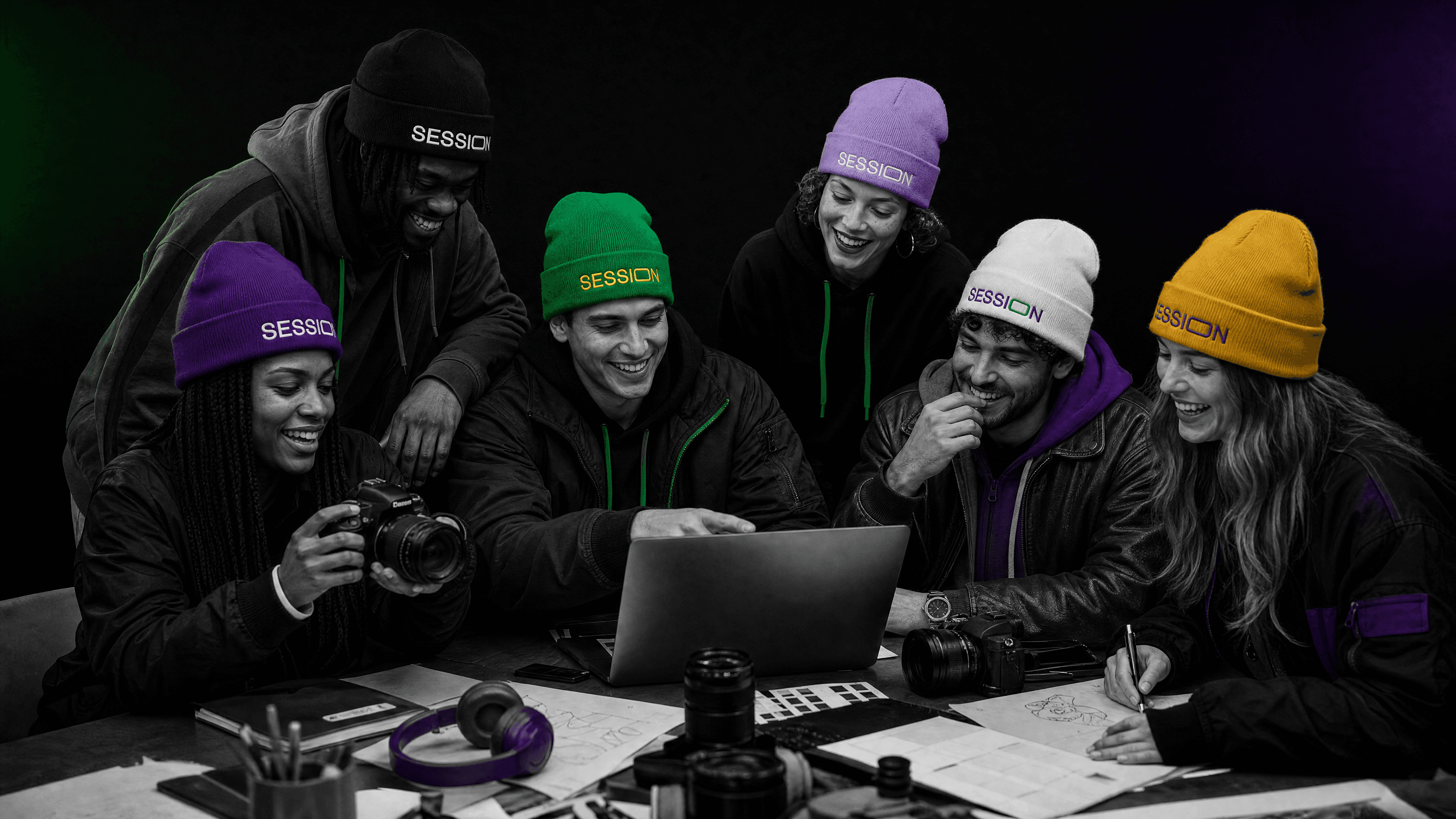 Friends wearing colorful Session Zone beanies while gathered around a laptop with cameras and sketches.
