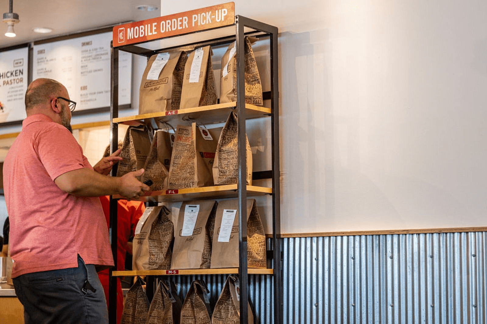 Image of a man picking up an online order from the Chipotle "Mobile Pick-ups" kiosk.