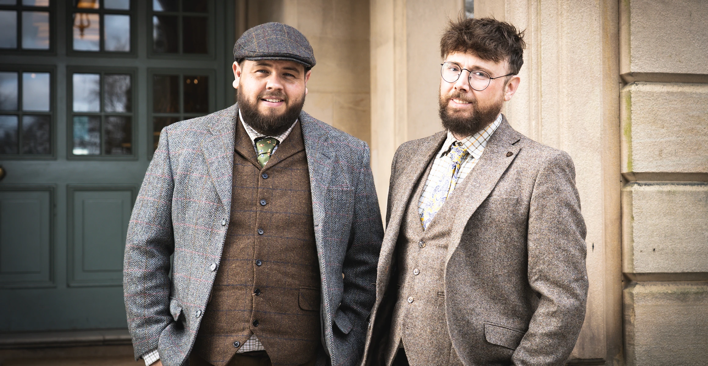 Two men, Adam Yeomans and Ben Fox of Hartingtons Heritage Tours, in Derbyshire. They wear tweed suits in brown and grey and one wears flat cap