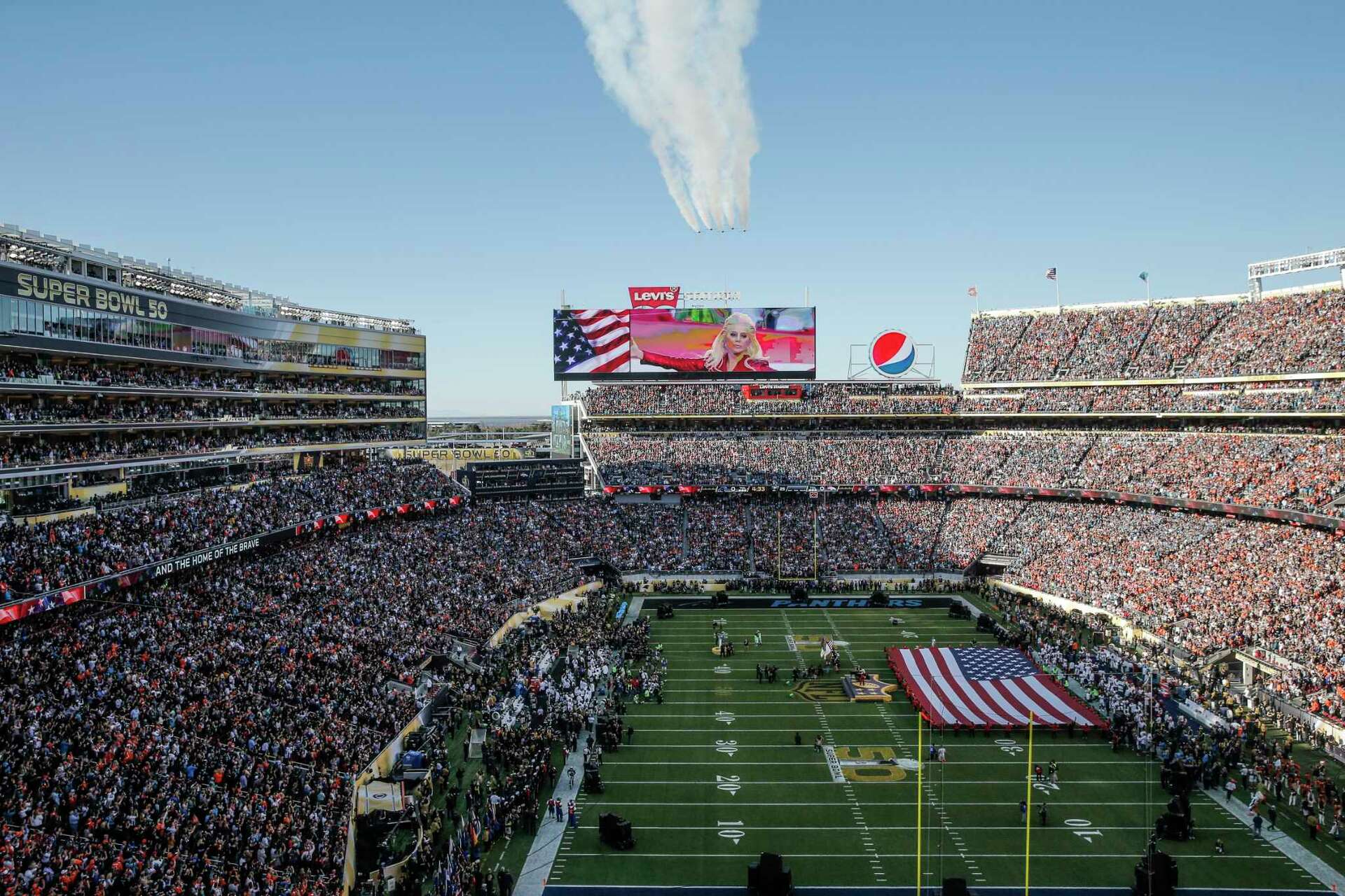 A talent recruiter with a soft smile working on her laptop in the office. The angle is on her face so we can't see what's is on the screen. She is wearing a blazer 
