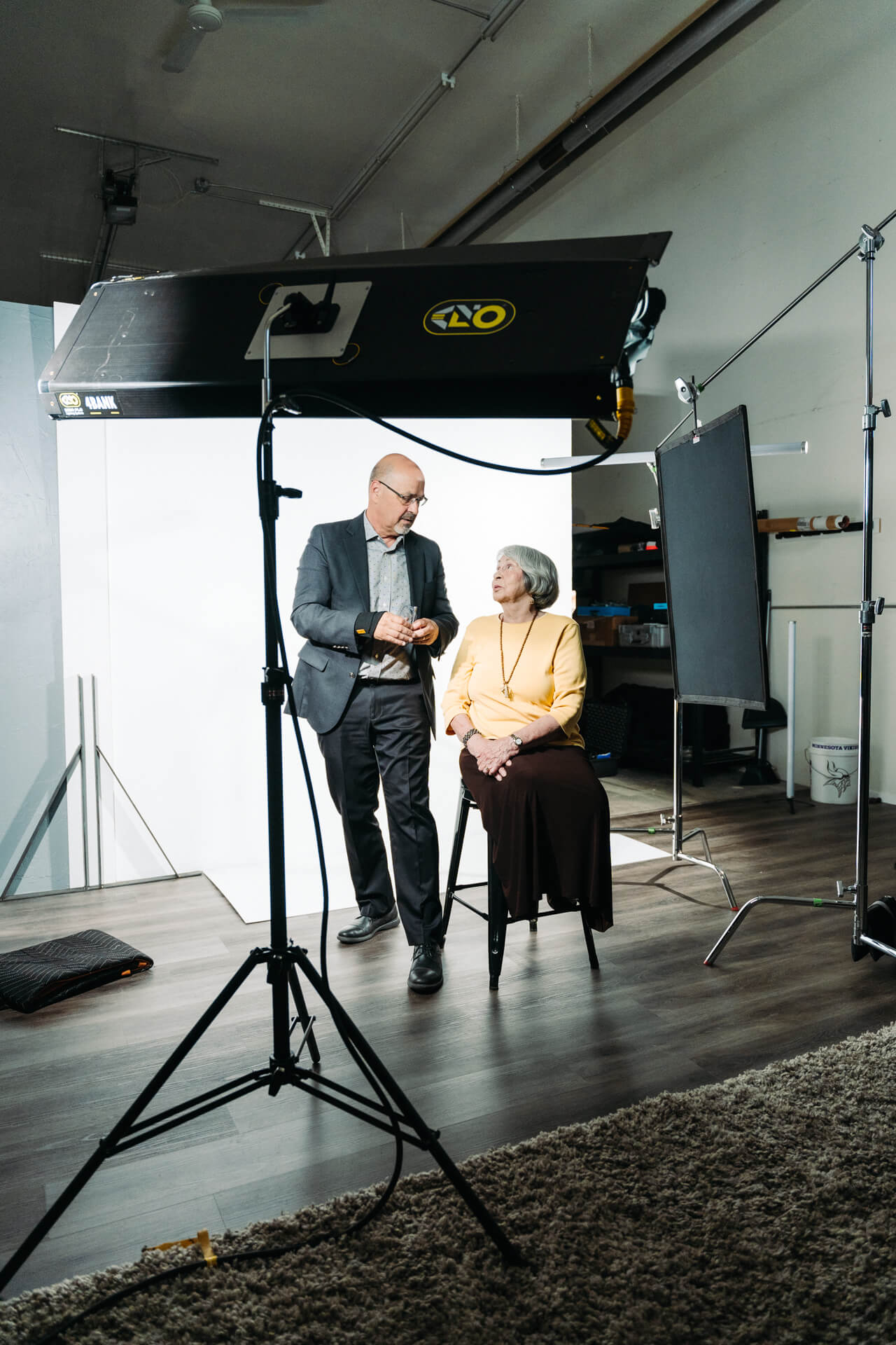 Mike and elder female talking in front of backdrop