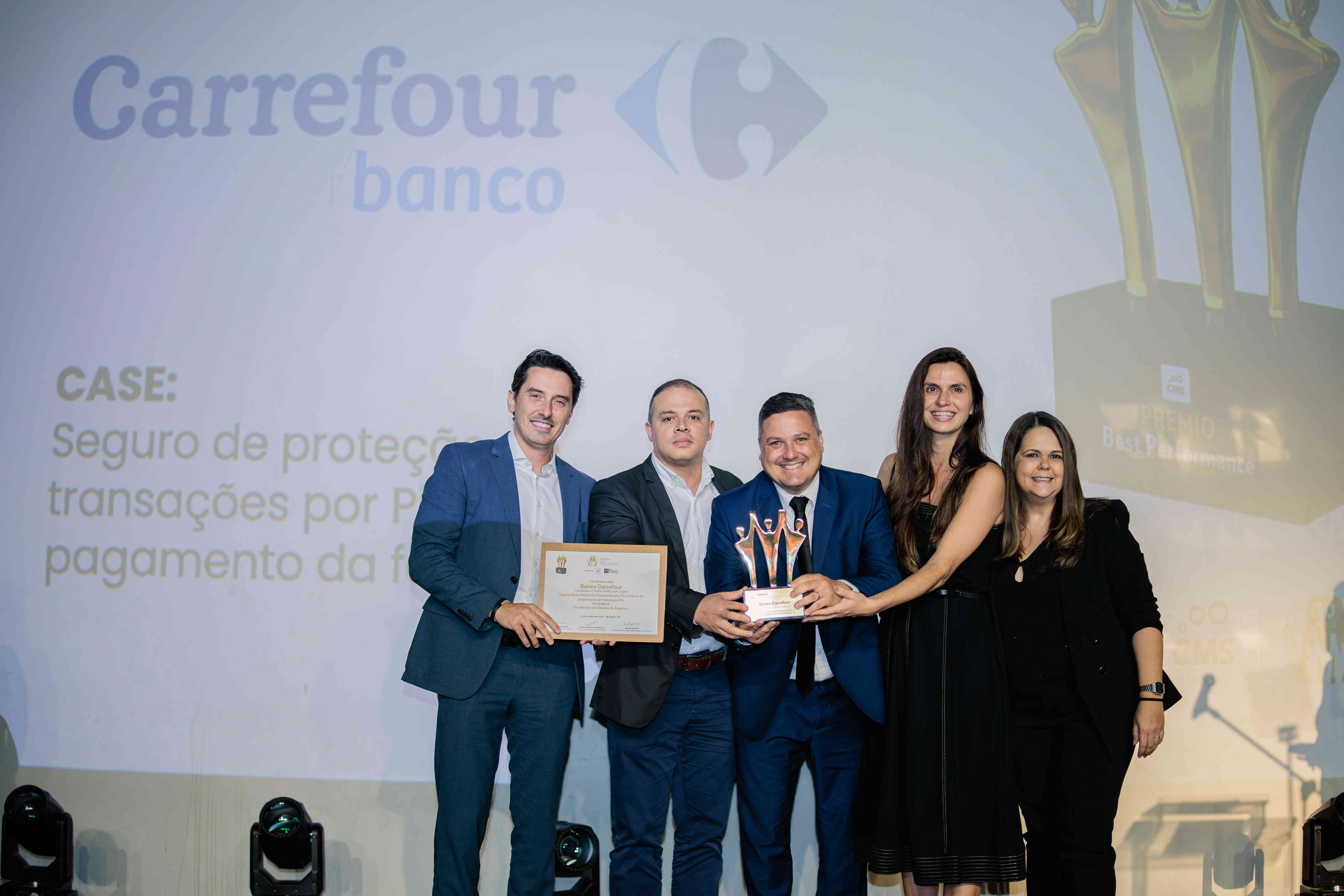 Executivos do Banco Carrefour posando com troféu ouro e certificado no palco do Prêmio Best Performance 2025