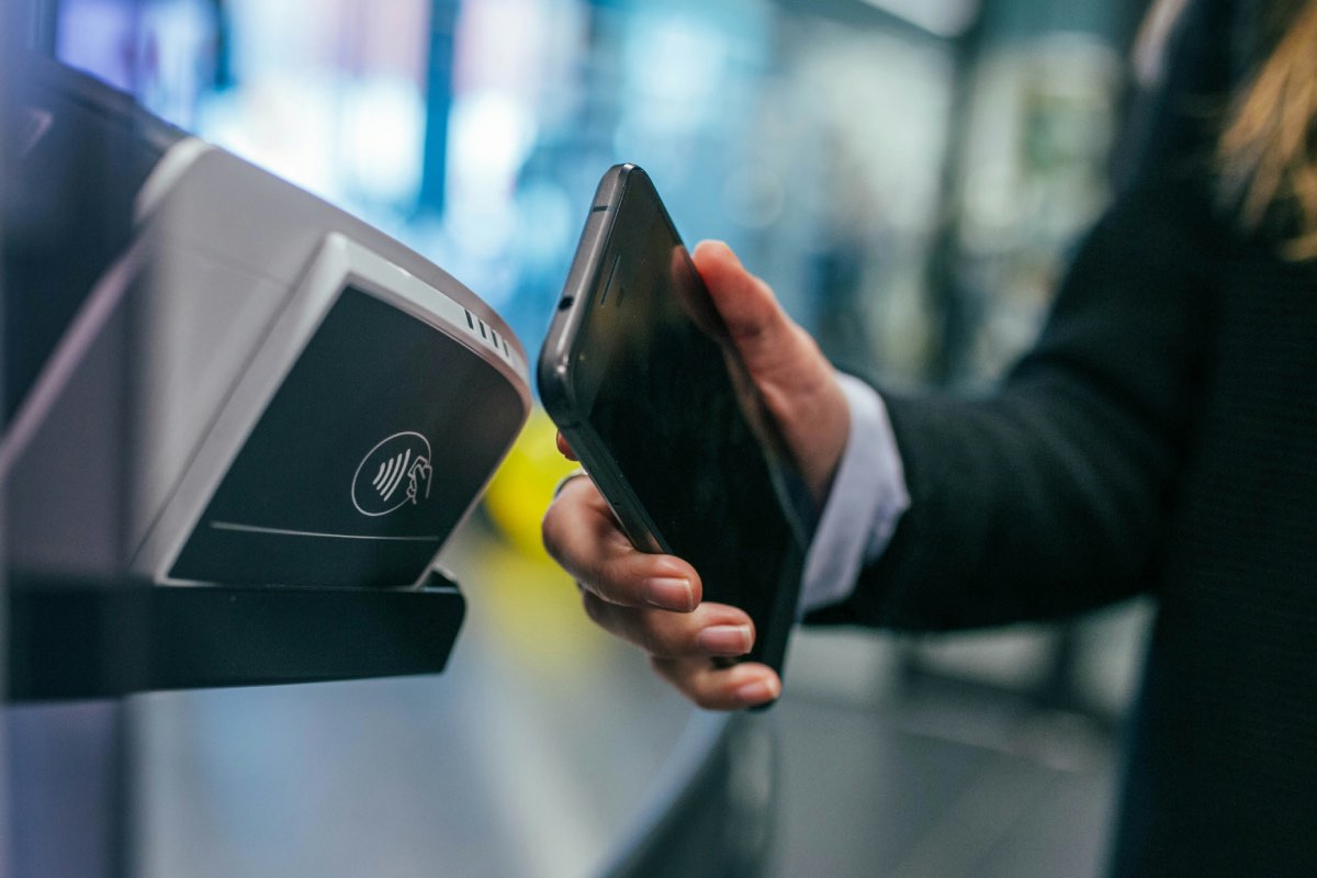 een persoon die hun telefoon dicht bij een POS houdt om te betalen