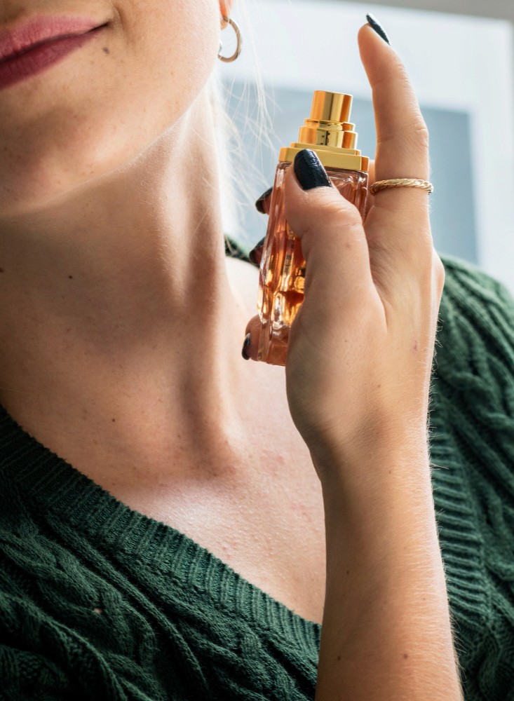 A person applying perfume in her neck