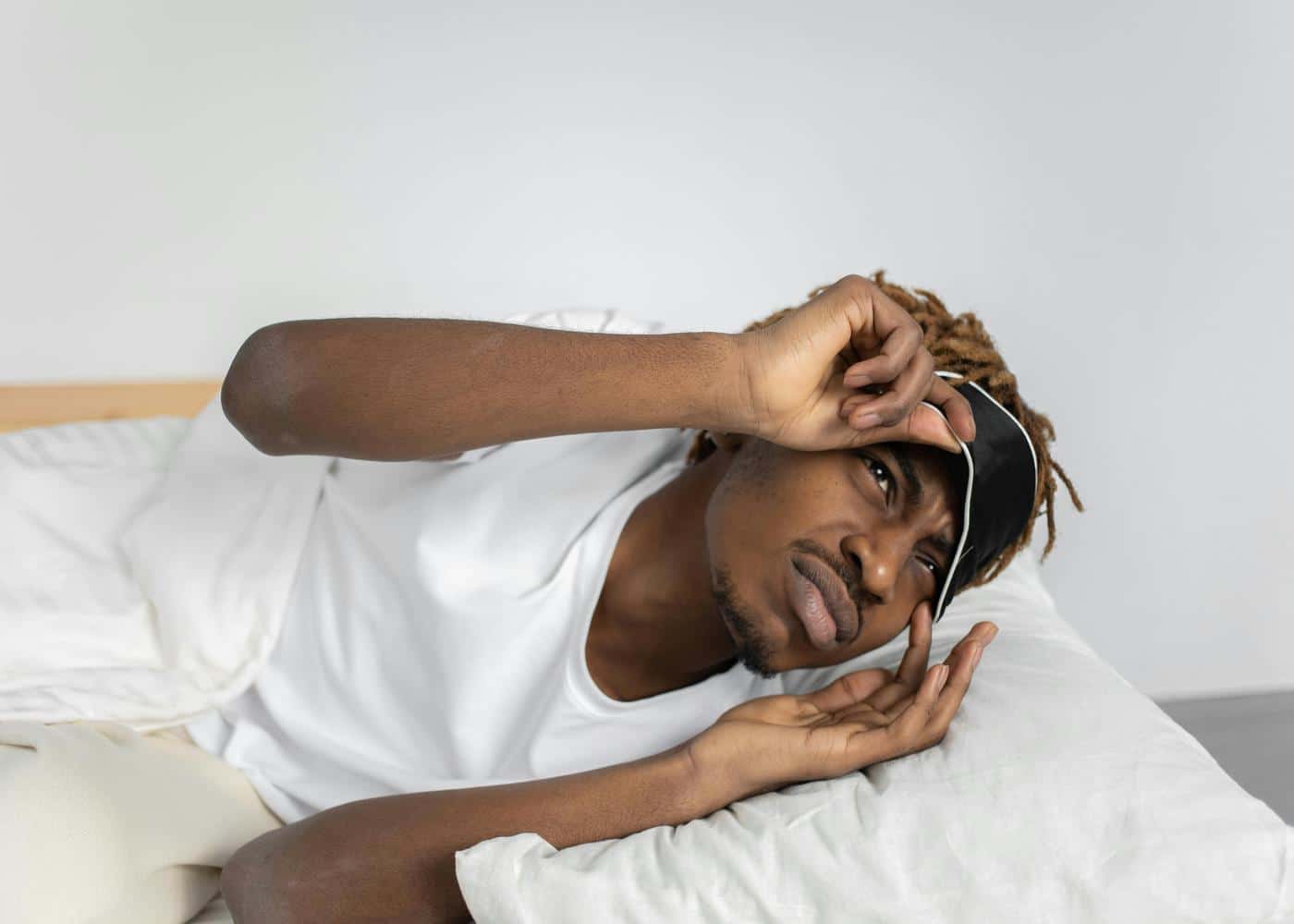 Man in bed taking off sleep mask