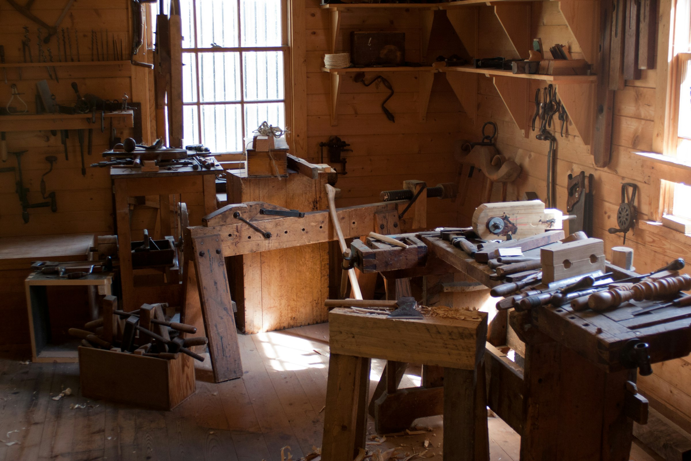 A woodworking shop with benches, clamps and hand tools in window light