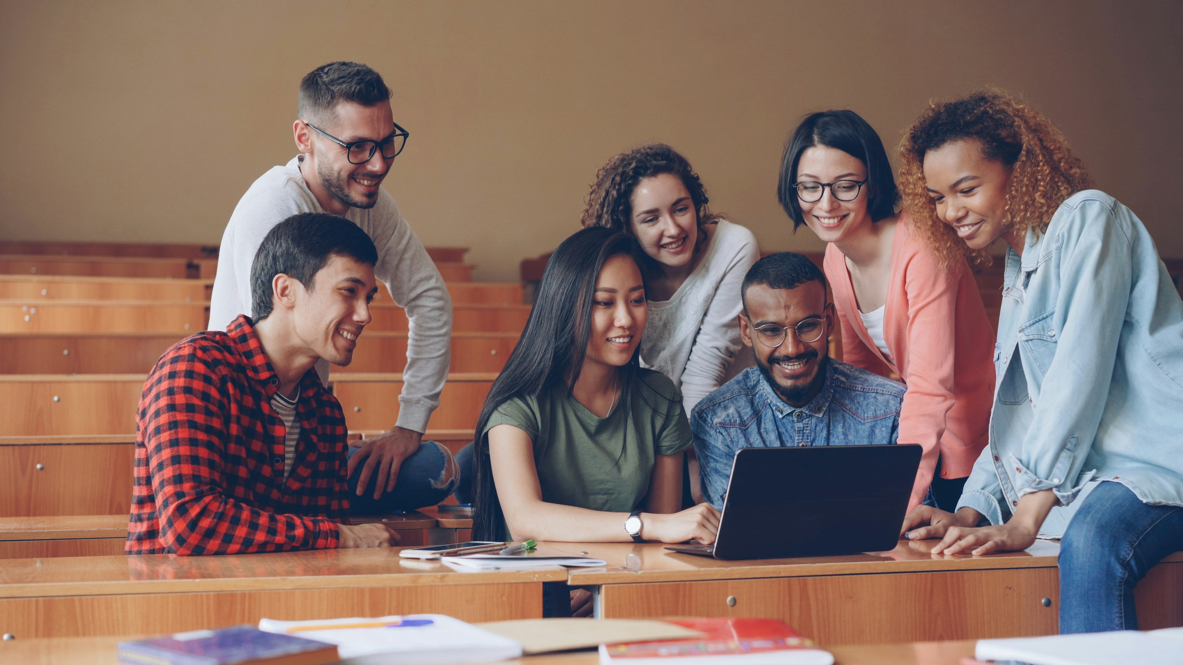 Diverse group of students collaborating around a laptop