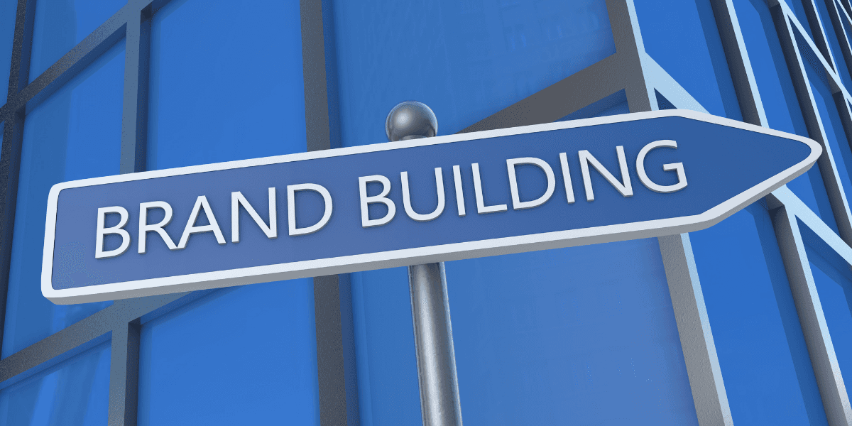 Brand Building sign pointing forward against a contemporary blue corporate building backdrop.