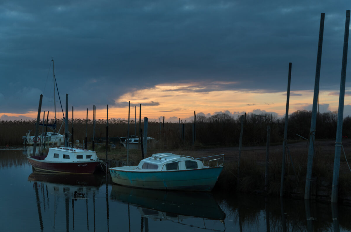 Le port des Tuiles, quelques bateaux sur l'eau, un coucher de soleil.