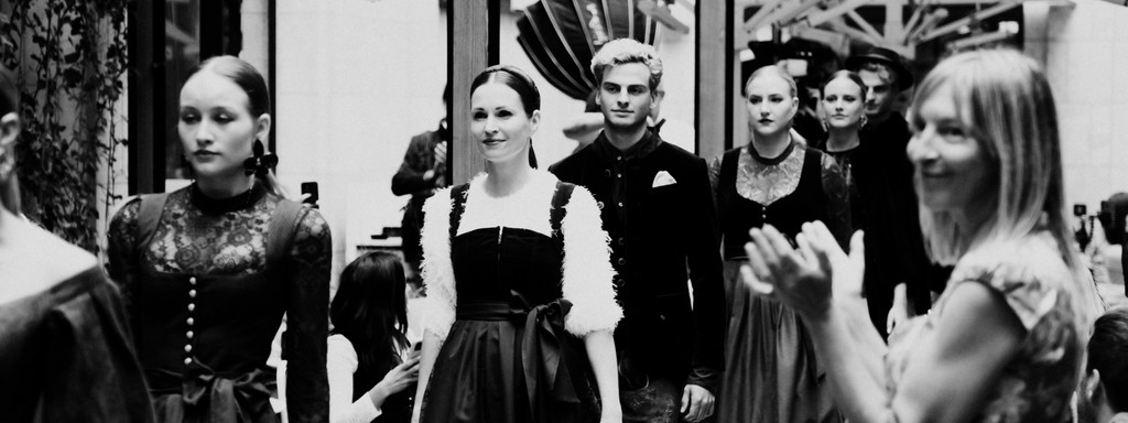 Black-and-white image of models wearing traditional Bavarian attire at an event