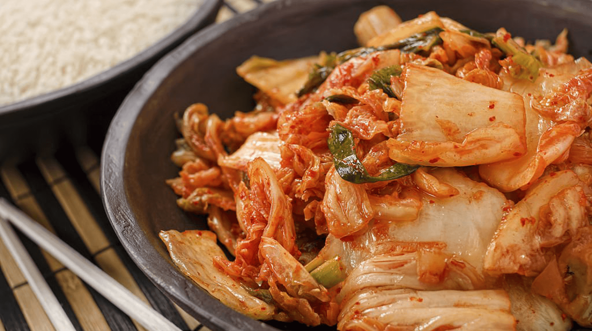 Close-up view of traditional Korean kimchi served in a black ceramic bowl.