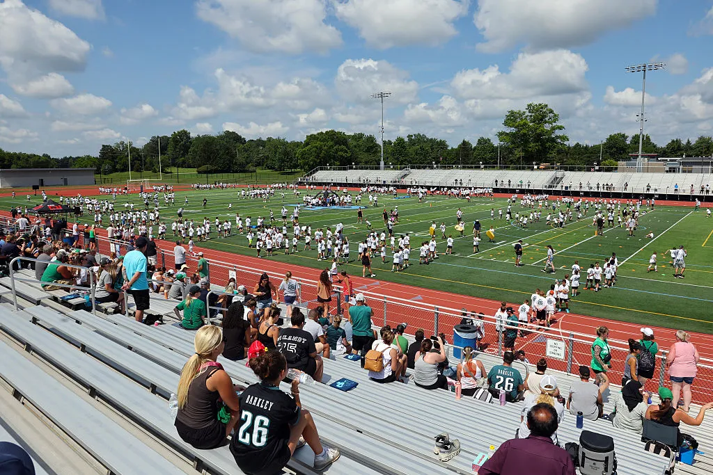 Aerial view of an intersecting dirt pathway forming an X-shape surrounded by lush greenery and arid, rocky terrain, illustrating a contrasting landscape.