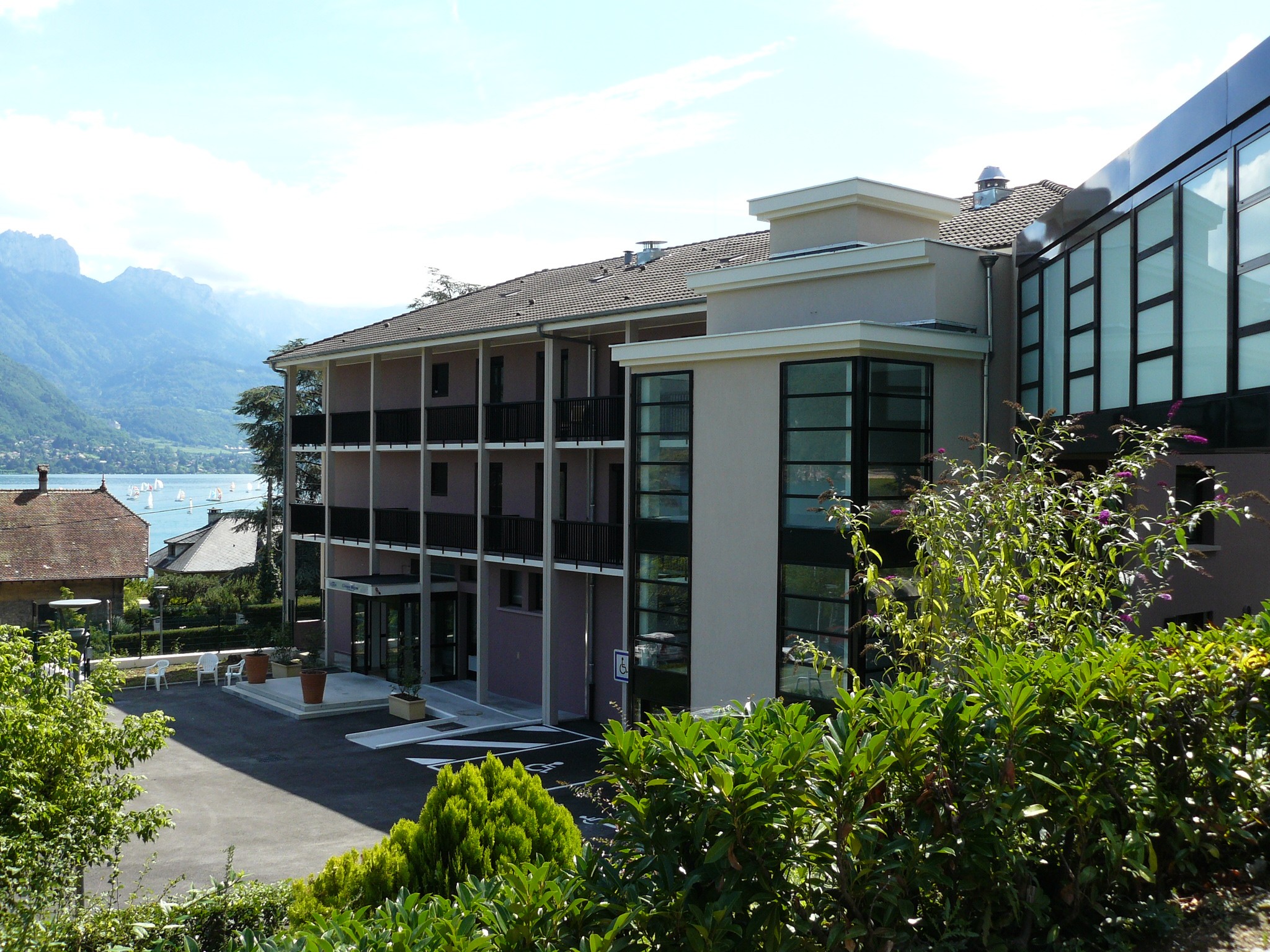 Modern residential building with wood and white exterior, green lawn, surrounding vegetation, and clear blue sky