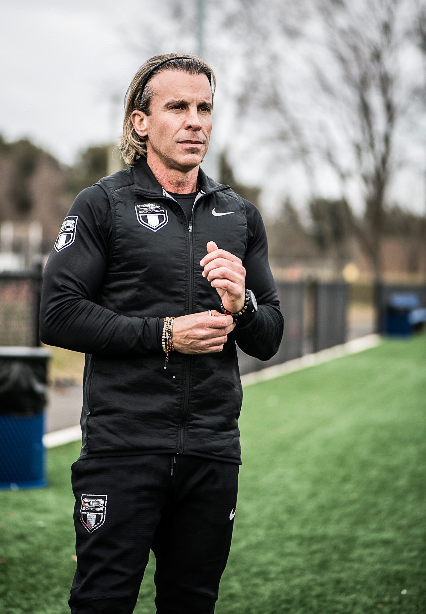Man in black track suit on a track. Coaching or athlete.