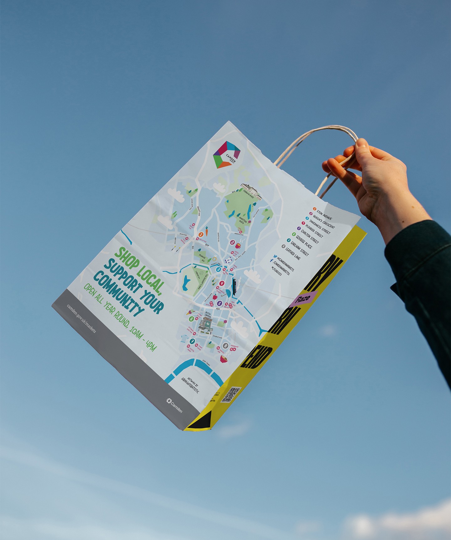 Hand holding a paper bag that has a map of Camden Borough and marks Camden Markets