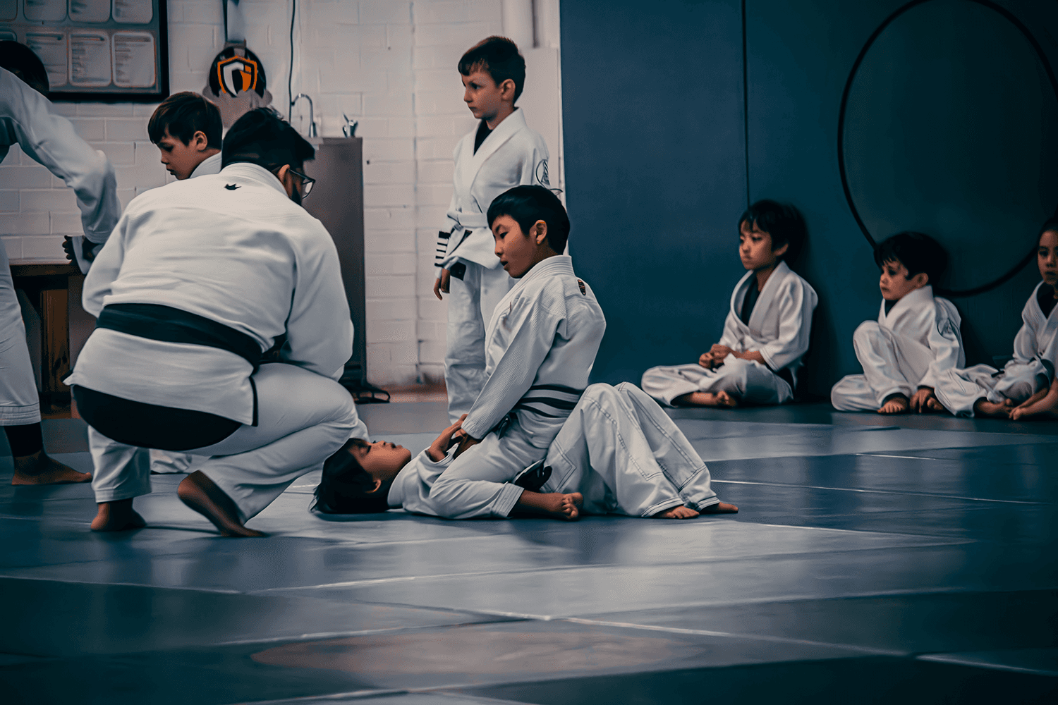 Children practicing Jiu Jitsu techniques with instructors supervising