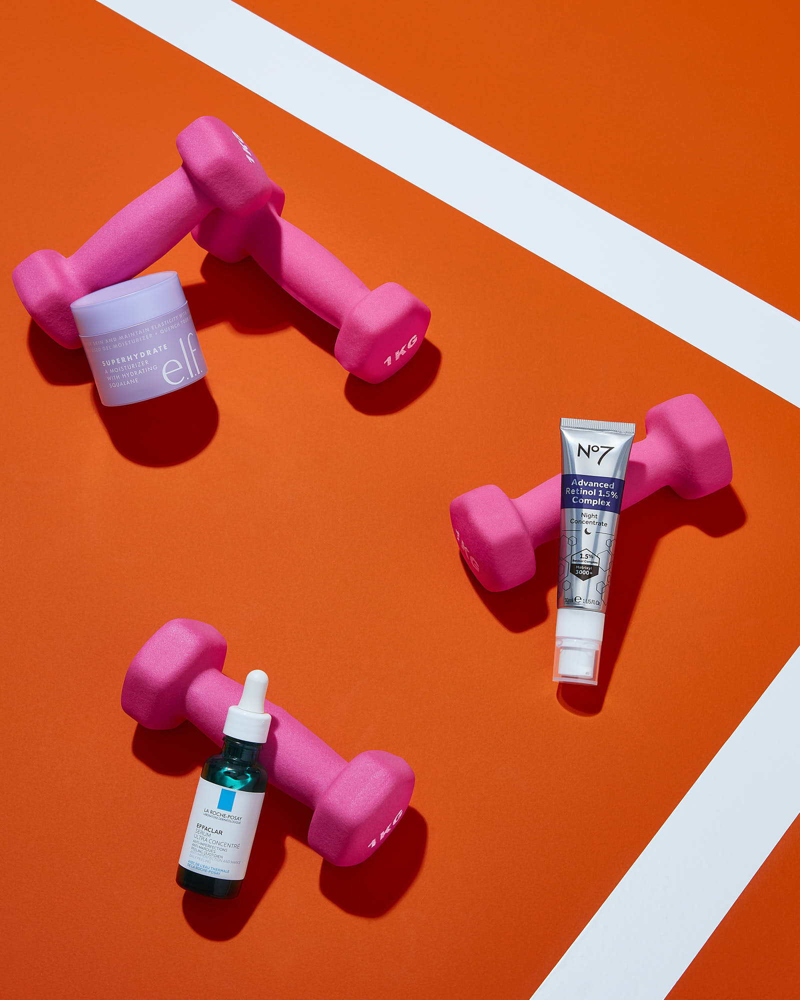 Three pink dumbbells are positioned on a bright orange surface, highlighting a fitness theme.