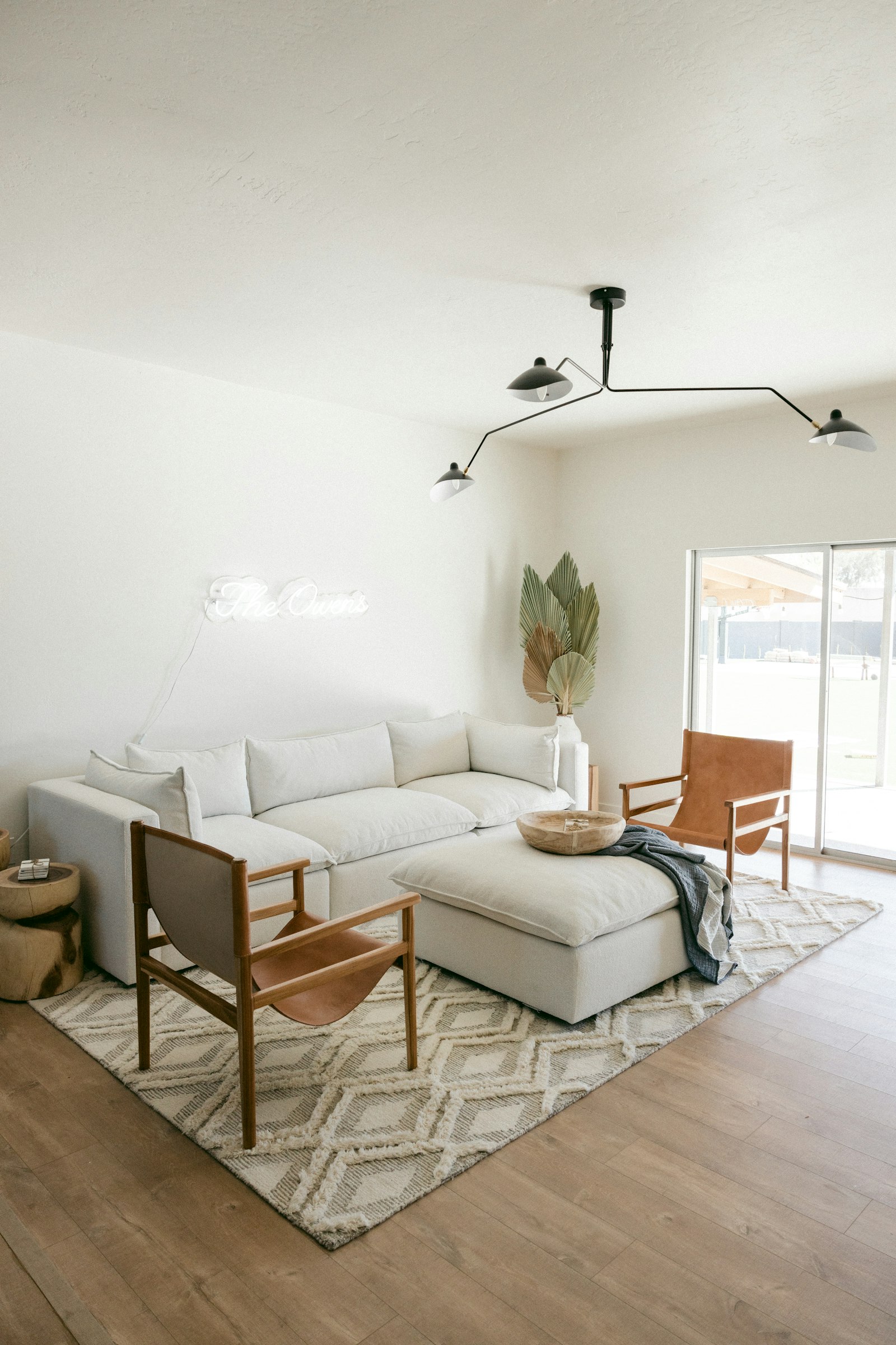 A white sofa beside a wooden chair in a bright room