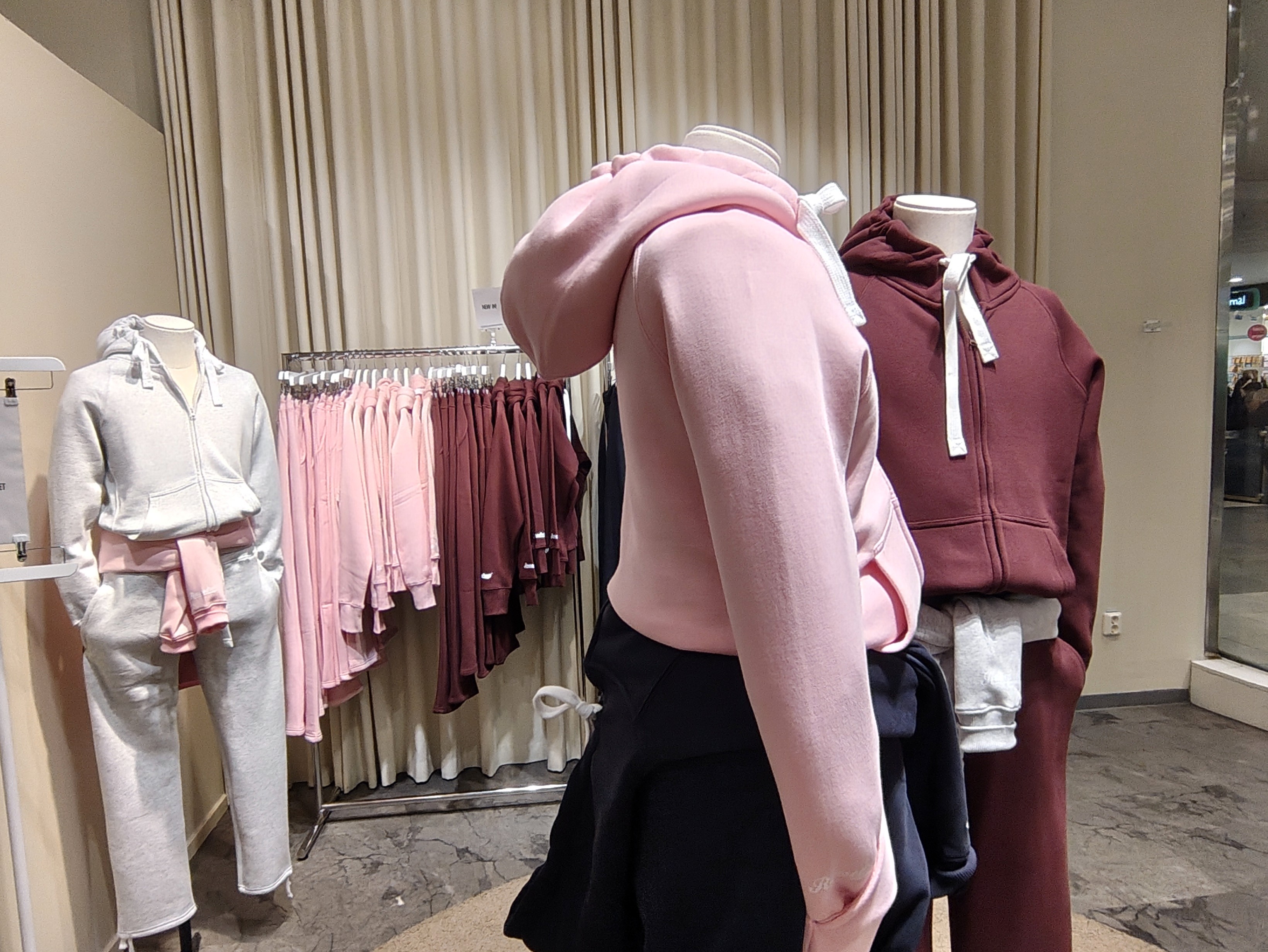 Beige colored store with manequins wearing different Russemerch garments in pink, maroon and light grey