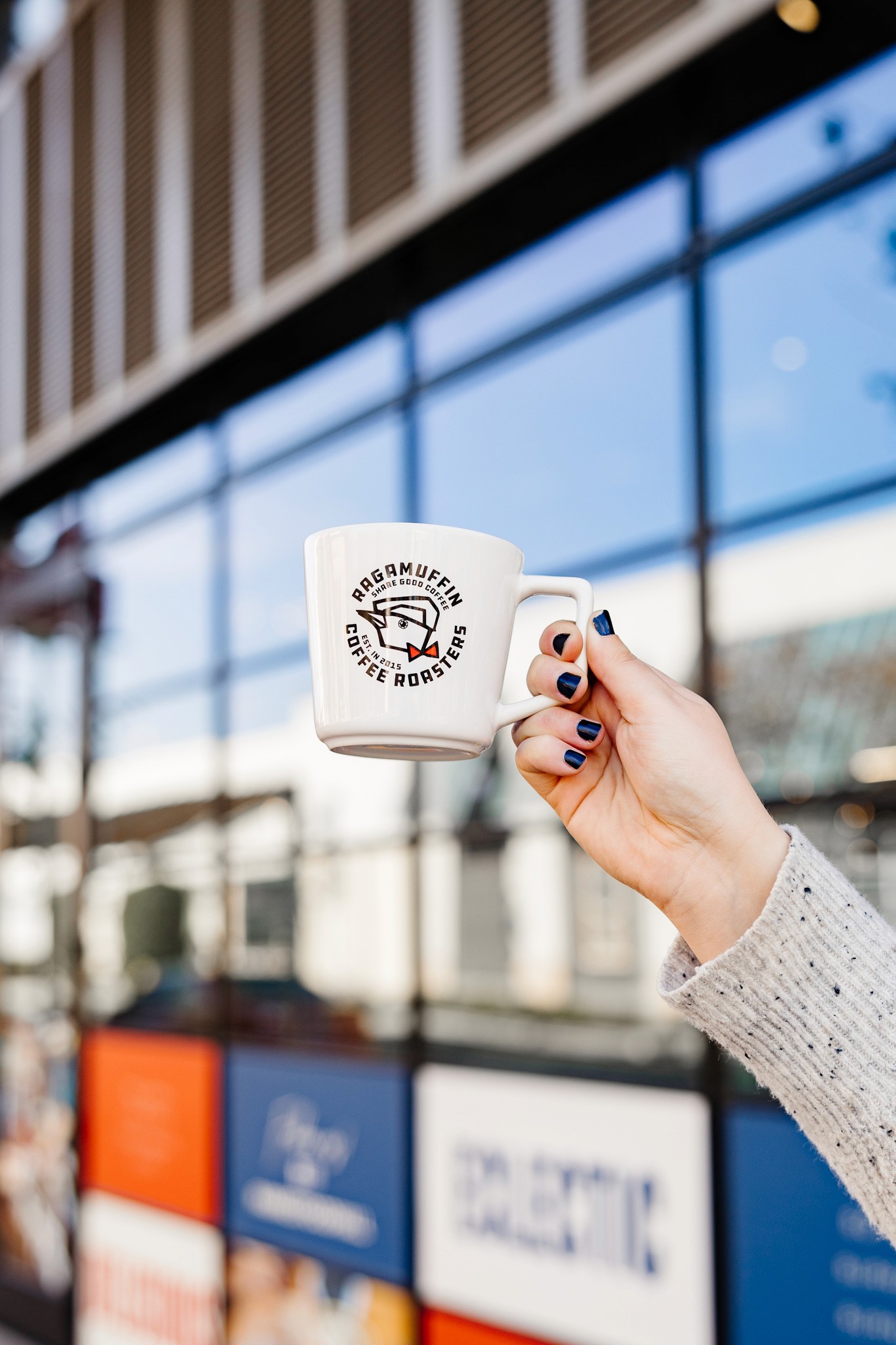 Hand holding Ragamuffin branded coffee mug outdoors