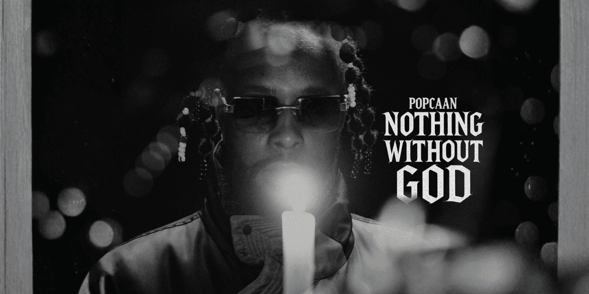 Popcaan holding a candle, reflecting spirituality, with the album title 'Nothing Without God' prominently displayed.