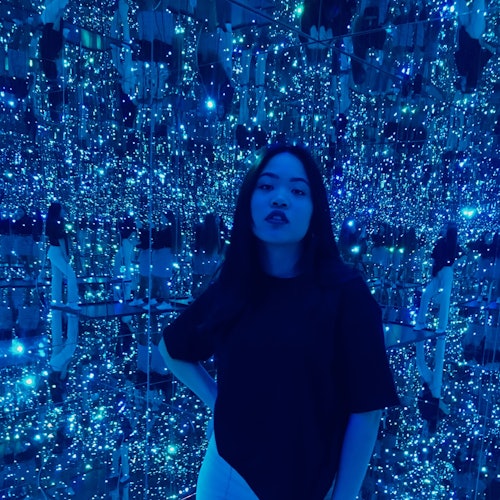 A woman stands in a room filled with blue LED lights and reflective surfaces, creating an immersive, sparkling backdrop.