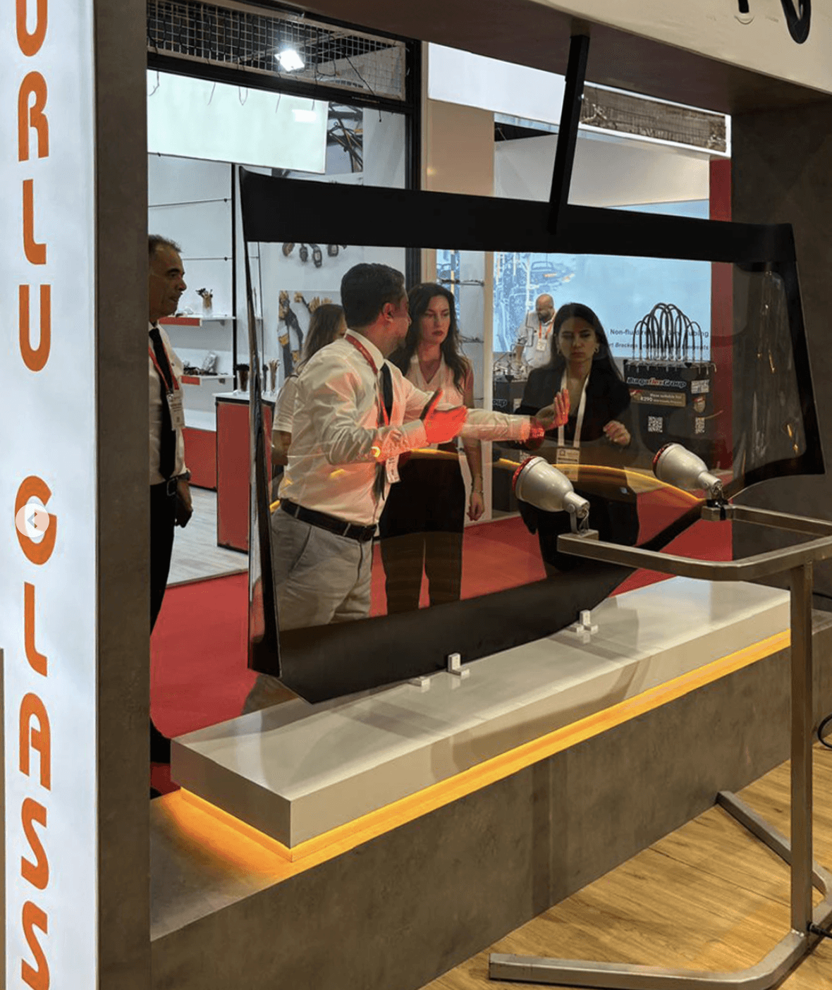 Real automobile glass products displayed on dedicated illuminated bases at the Uğurlu Glass stand.