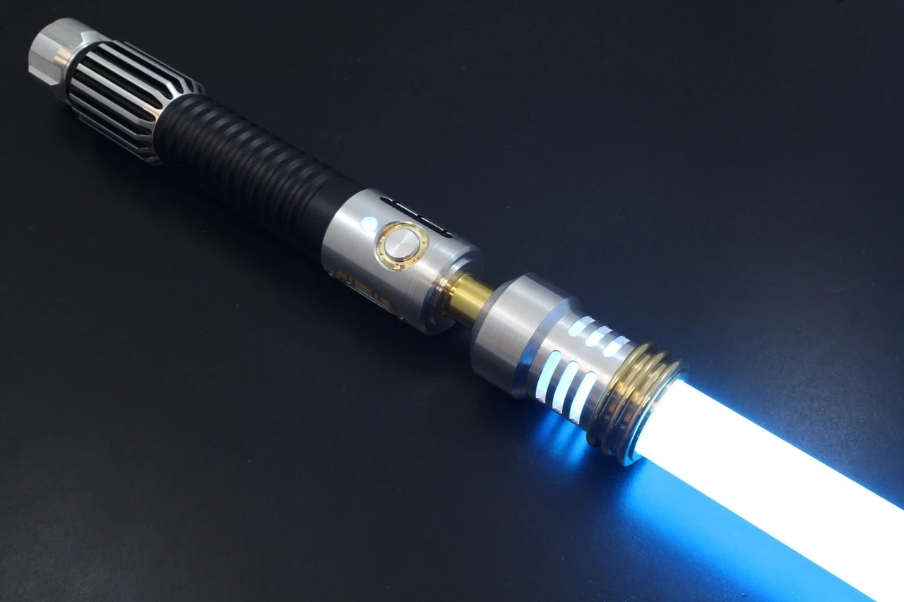 A glowing blue lightsaber with a metallic hilt, featuring intricate grooves and a black grip, rests on a smooth black surface, representing iconic sci-fi weaponry.