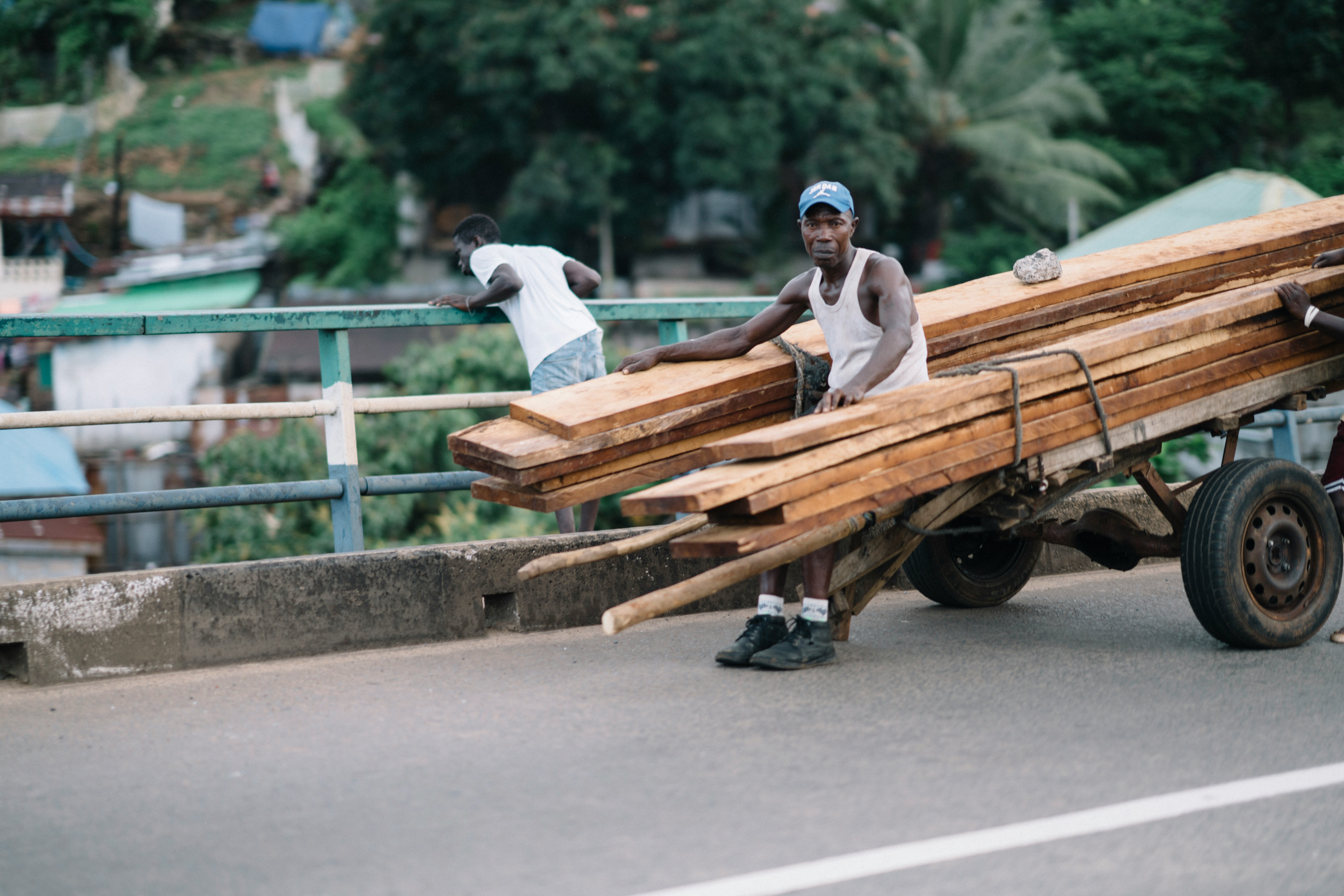 Man pulling cart loaded with lumber on a road