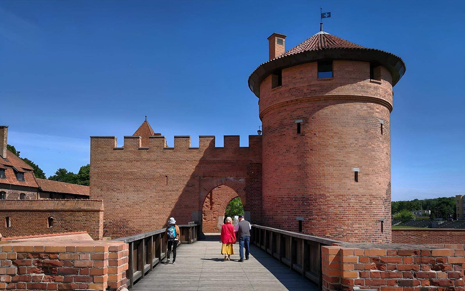 Visitors walking on a bridge towards Malbork Castle's entrance during an audio guide tour from Gdańsk.