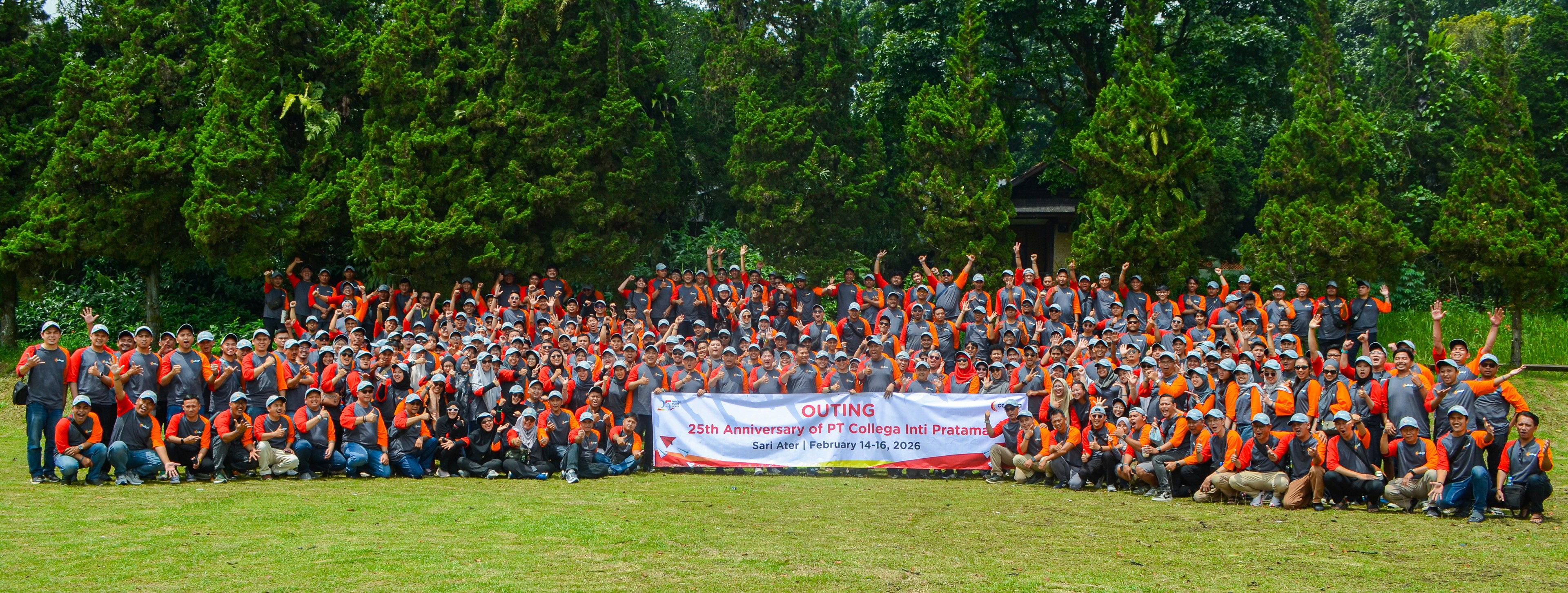 Ratusan karyawan mengenakan kaos seragam merah dan abu-abu berfoto bersama di lapangan rumput dengan latar pepohonan tinggi. Mereka memegang banner bertuliskan ‘Outing 25th Anniversary of PT Collega Inti Pratama, Sari Ater | February 14–16, 2026’ dan tampak bersemangat mengangkat tangan.