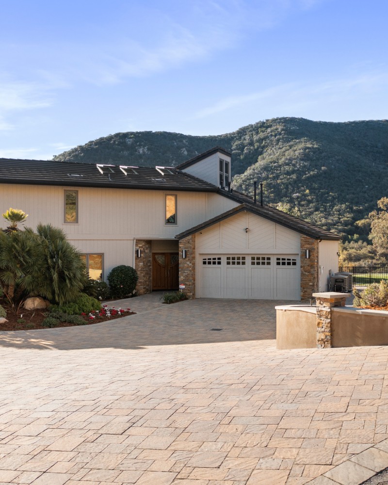 A smiling young man with crossed arms, wearing a plaid shirt and white t-shirt, poses against a dark background.