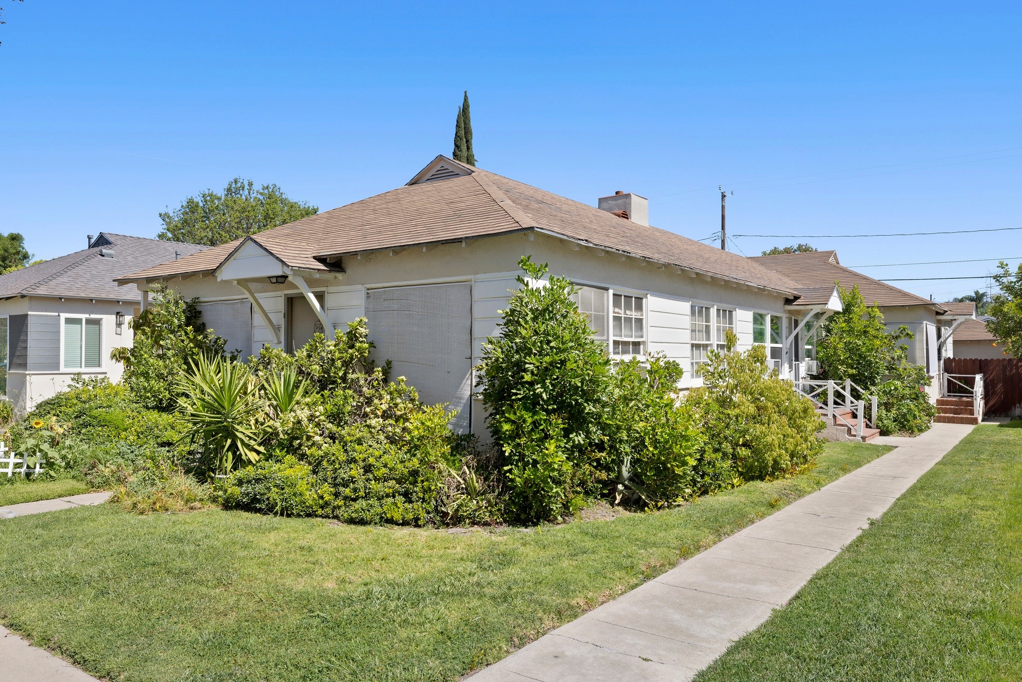 Angled exterior view of duplex with mature landscaping and shared walkway at 242 N Cordova property.