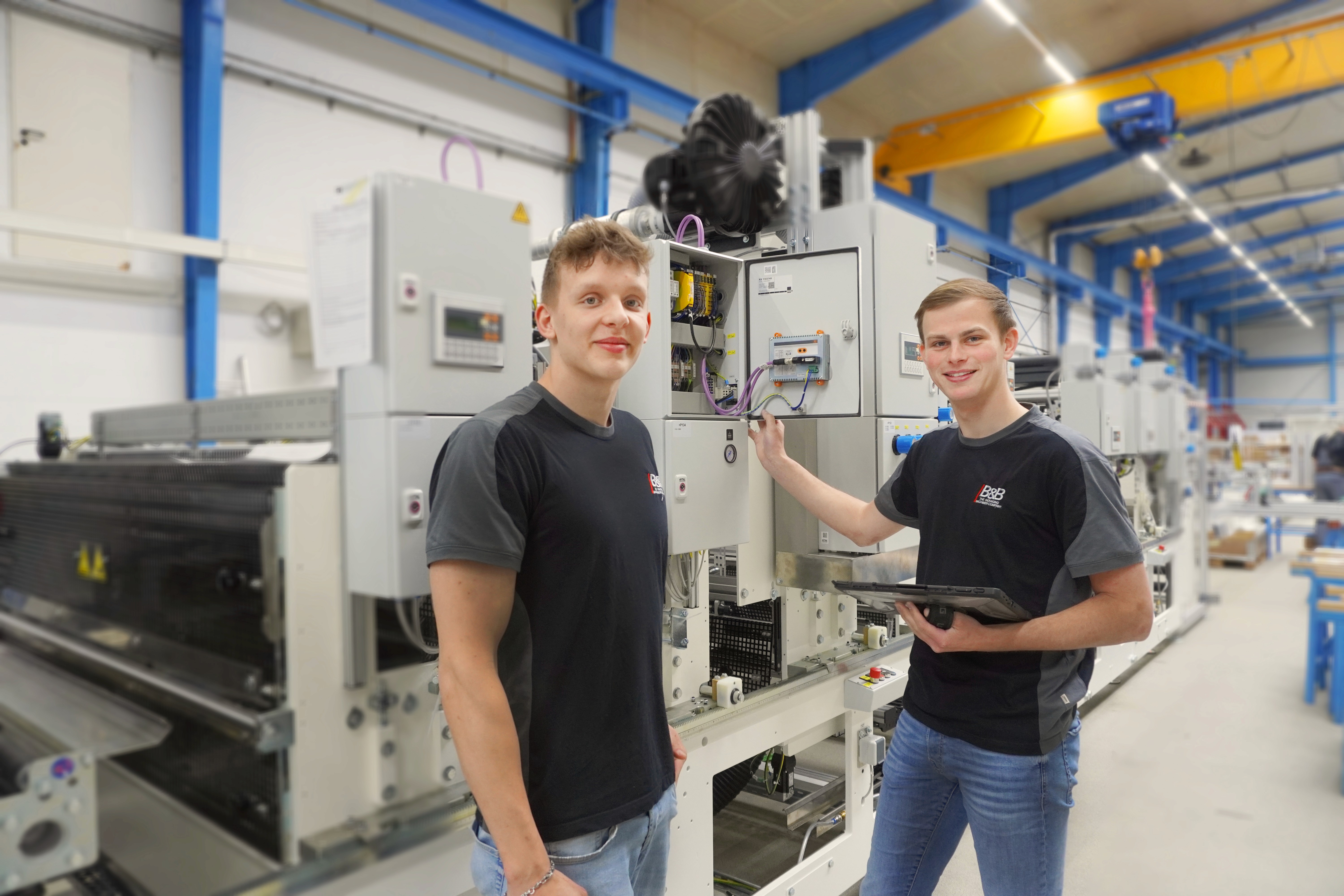 Two young men at an industrial machine. Technology, training.