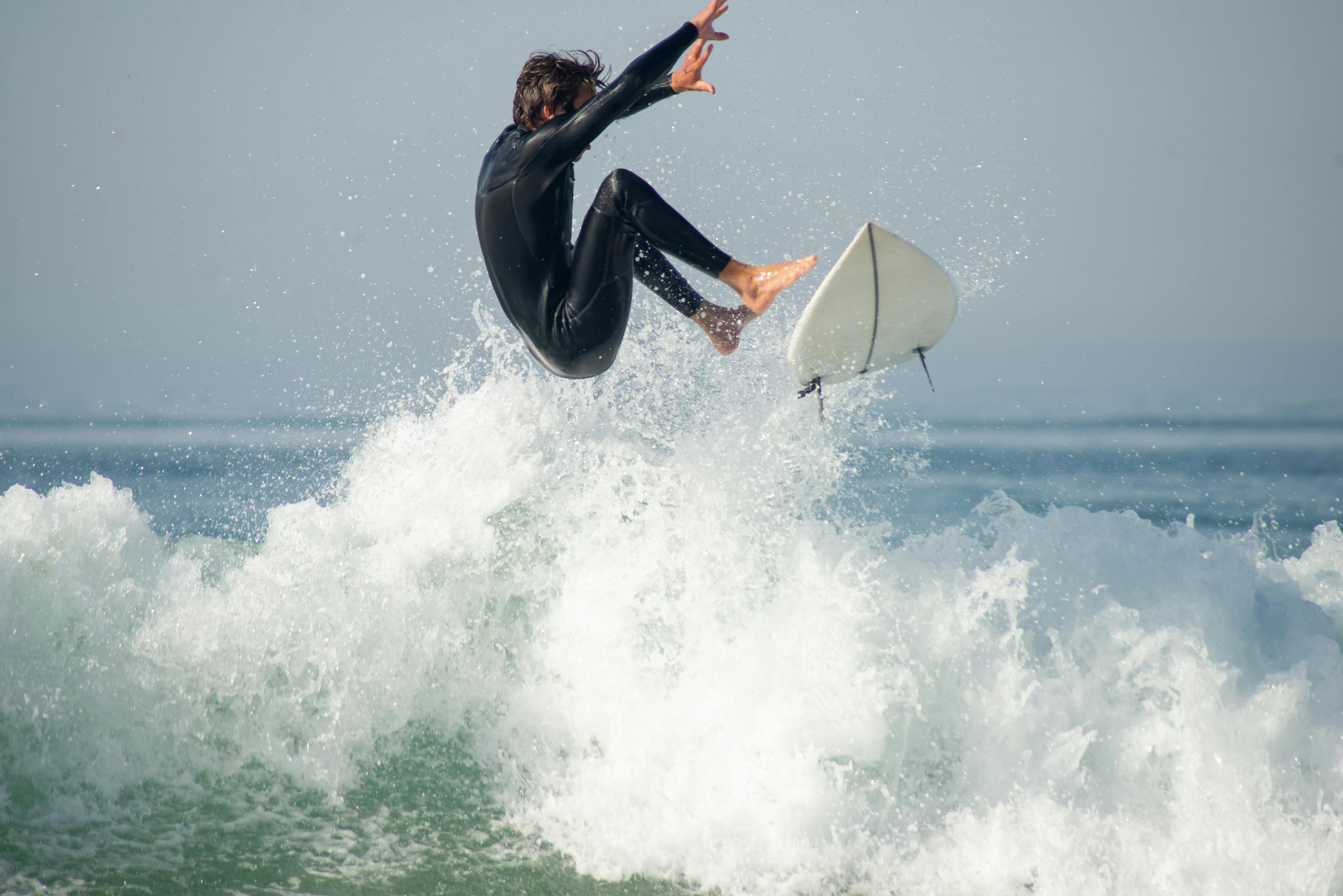 Surfer in wetsuit jumping on wave with surfboard – surfboard rental in atlantic-city.