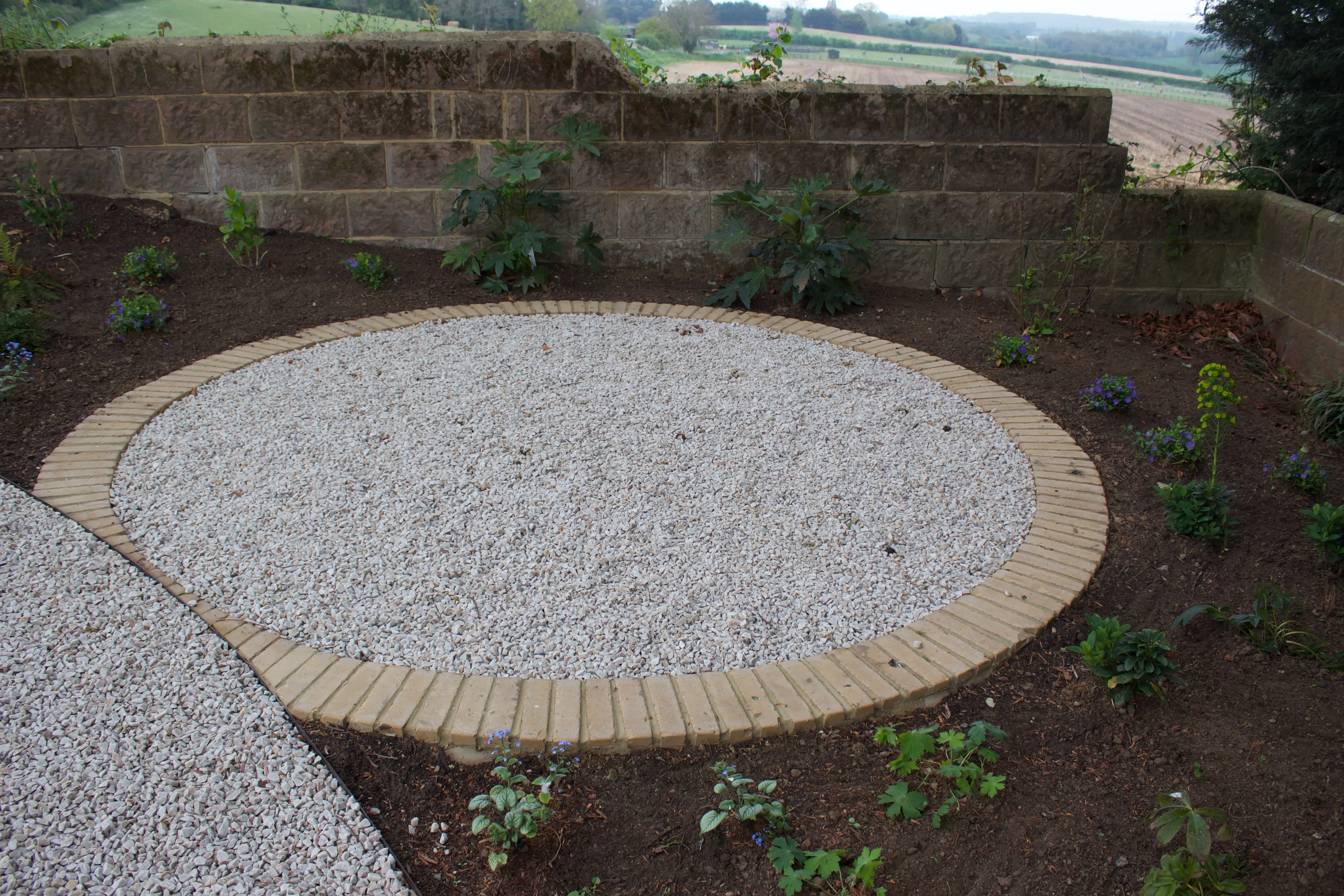 Circular stone platform surrounded by earth and small shrubs, set against a natural landscape.