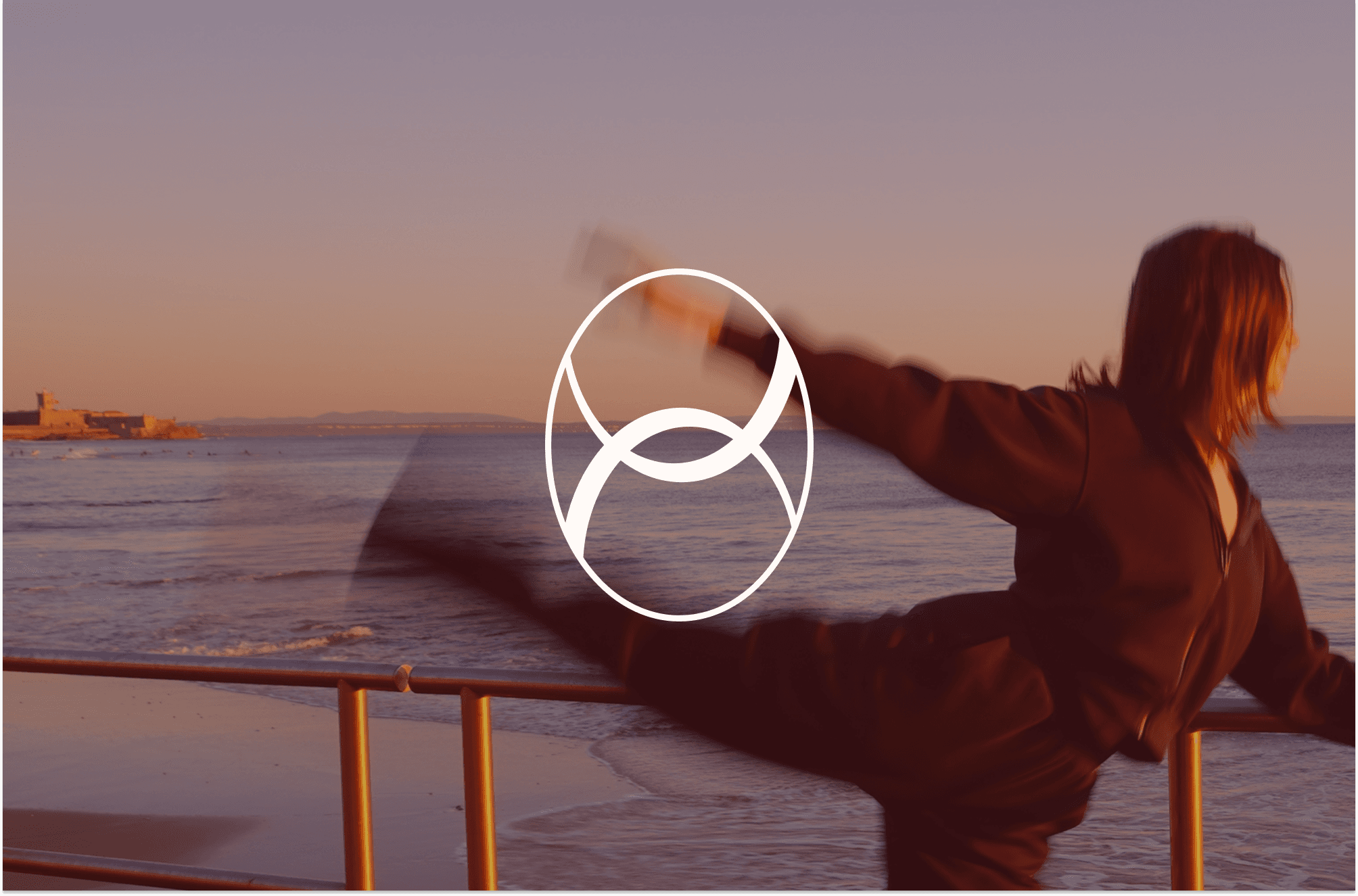 A woman doing a ballet arabesque at the beach, holding a barre.